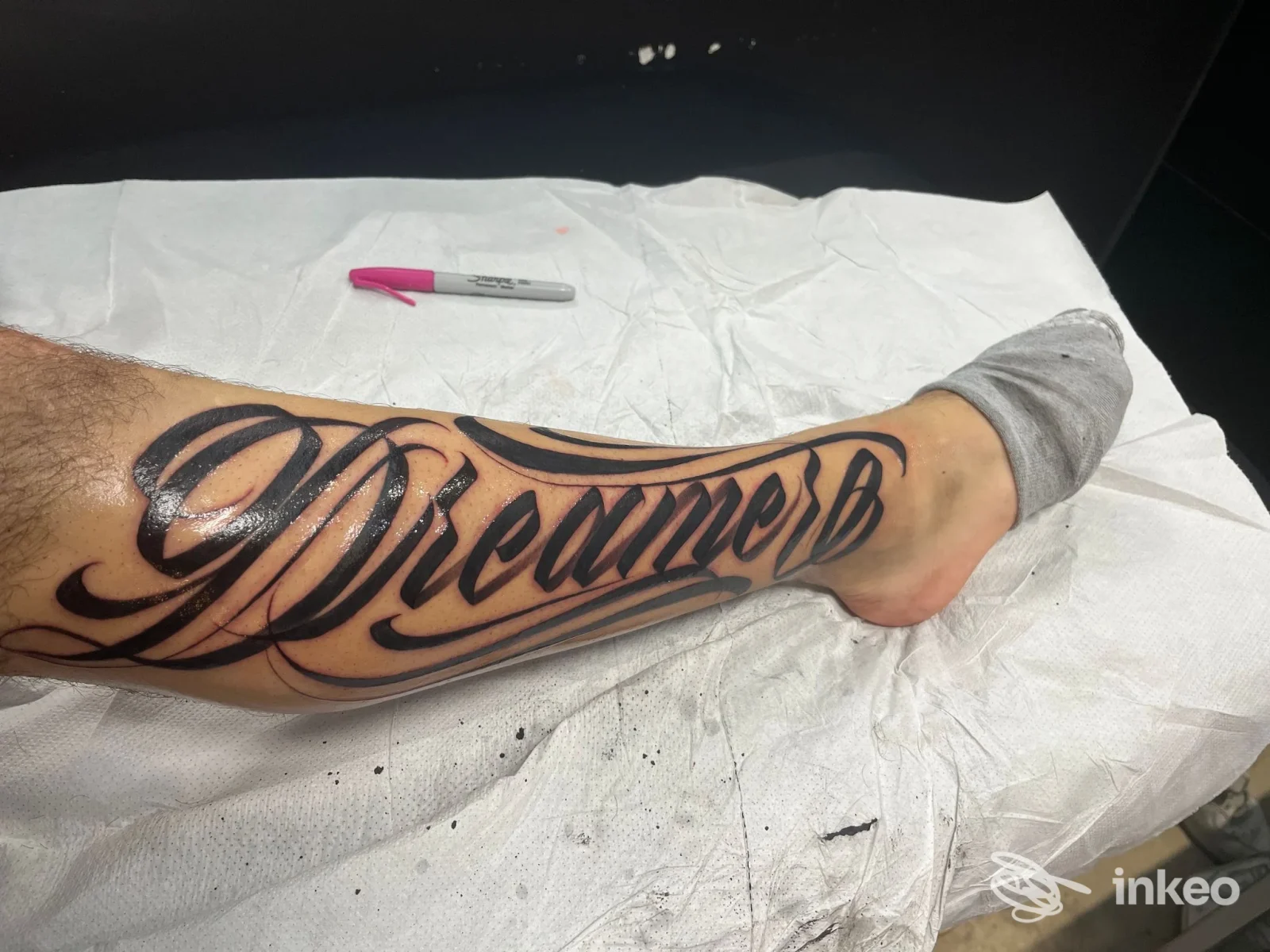 Gamba tatuata con lettering 'Dreamer', lavoro eseguito da Kosta Dorika Tattoo ad Ancona.