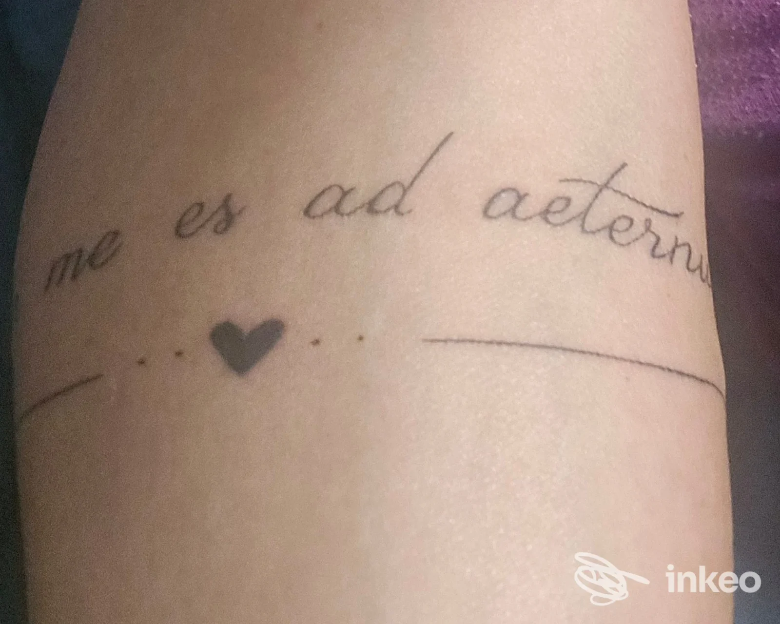 Primo piano di tatuaggio testuale in corsivo con piccolo cuore sull'avambraccio, realizzato al Legionarius Tattoo Studio a Grottammare.