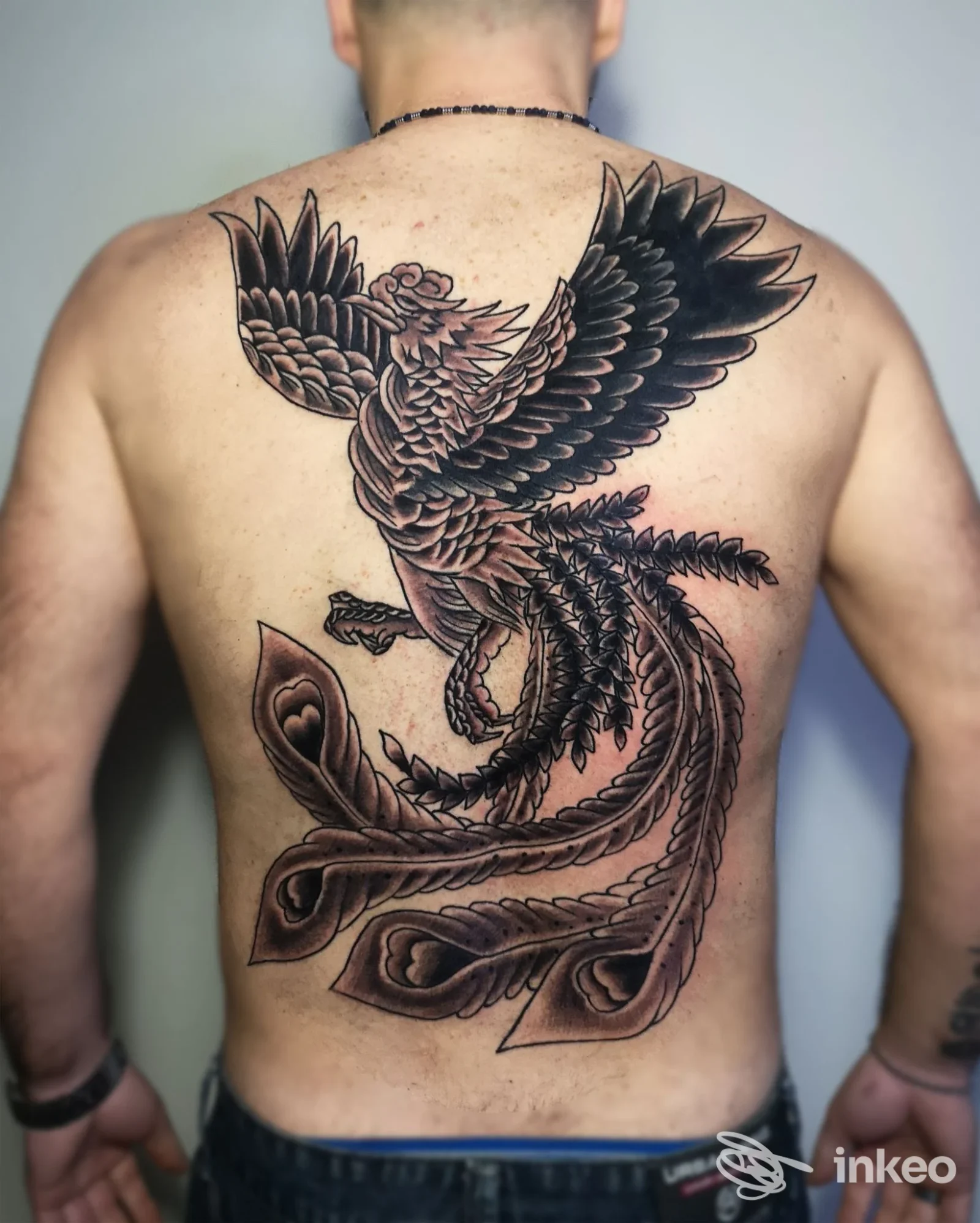 Grande tatuaggio dorsale raffigurante una fenice stilizzata sulla schiena di un uomo, Ink City Tattoo SBT, San Benedetto del Tronto.