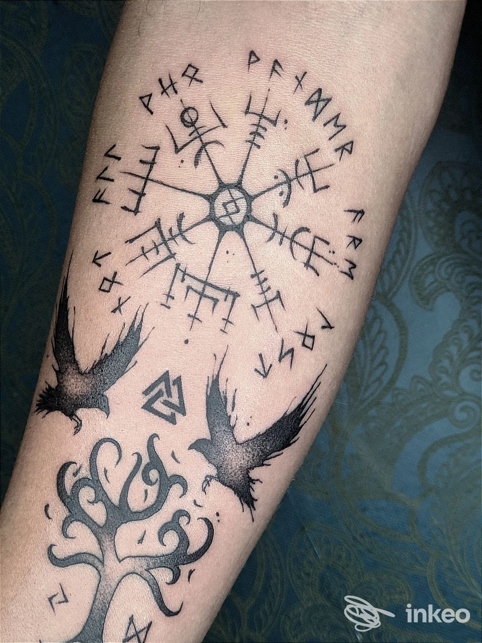 Tatuaggi su avambraccio con simbolo runico centrale e corvi, foto fornita da Kali Tattoo Studio, San Benedetto del Tronto.