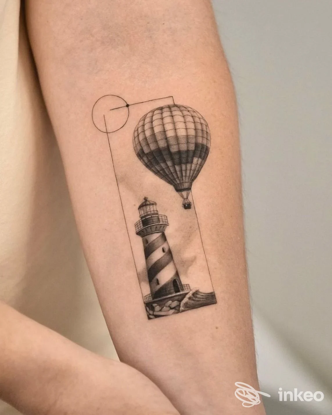 Tatuaggio in bianco e nero su avambraccio con faro e mongolfiera, immagine fornita da Marte tattoo planet, Tolentino.
