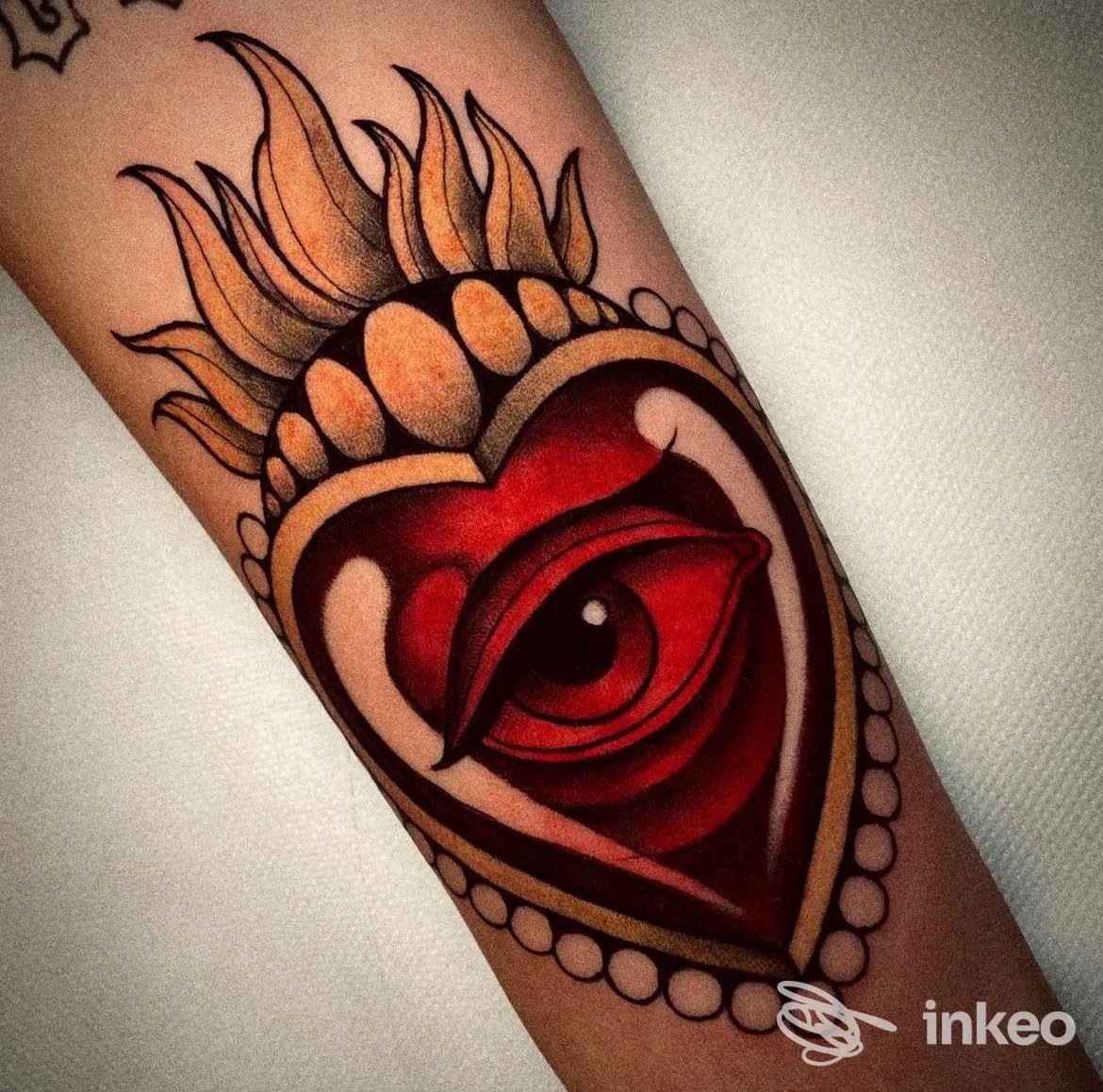 Tatuaggio colorato sull'avambraccio a forma di cuore con occhio, fotografato da NEST Tattoo Atelier a Piediripa.