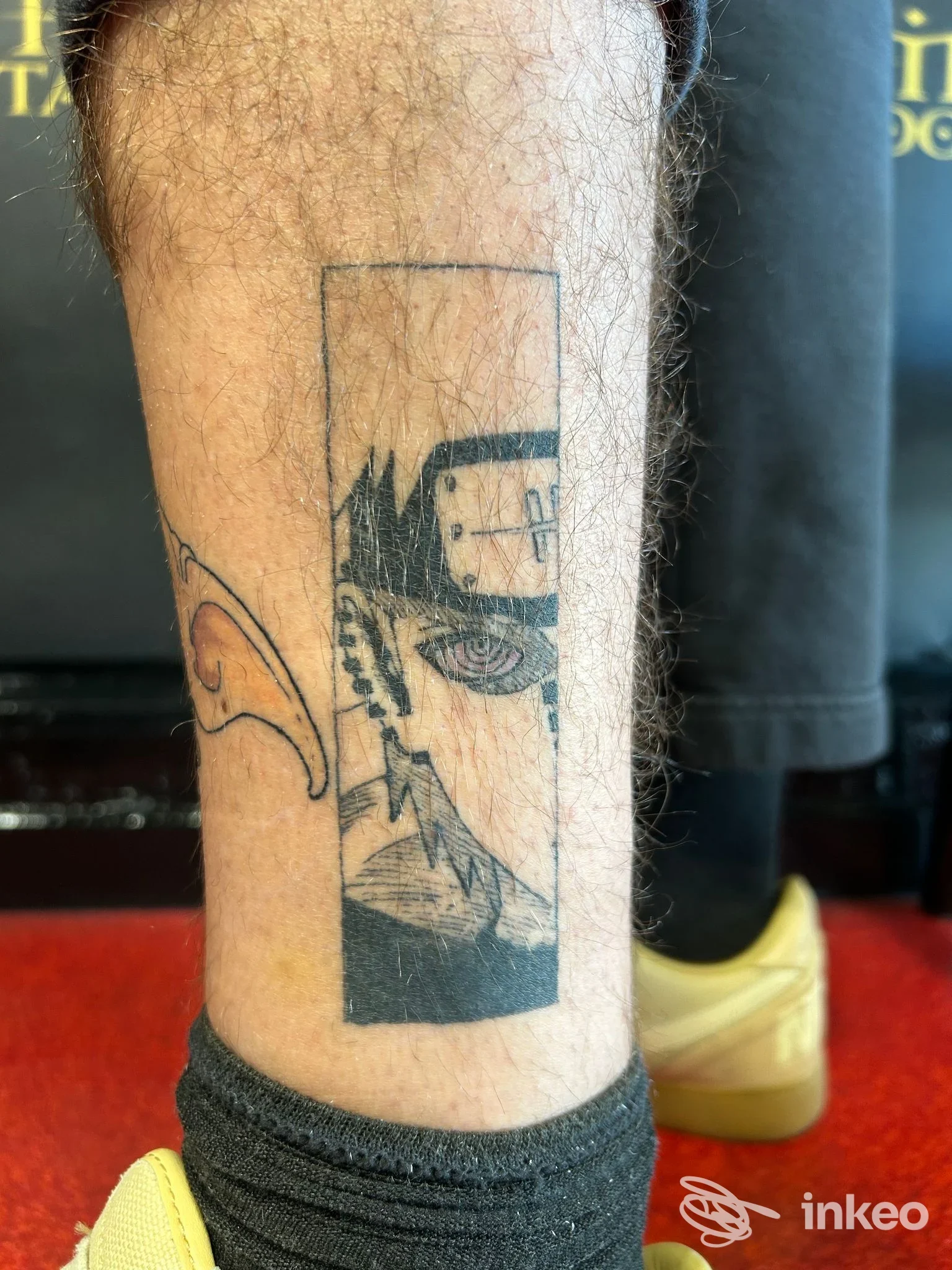 Polpaccio tatuato con pannello verticale nero raffigurante un volto stilizzato, foto fornita da Nichi Flowers Tattoo Artist, Ancona.