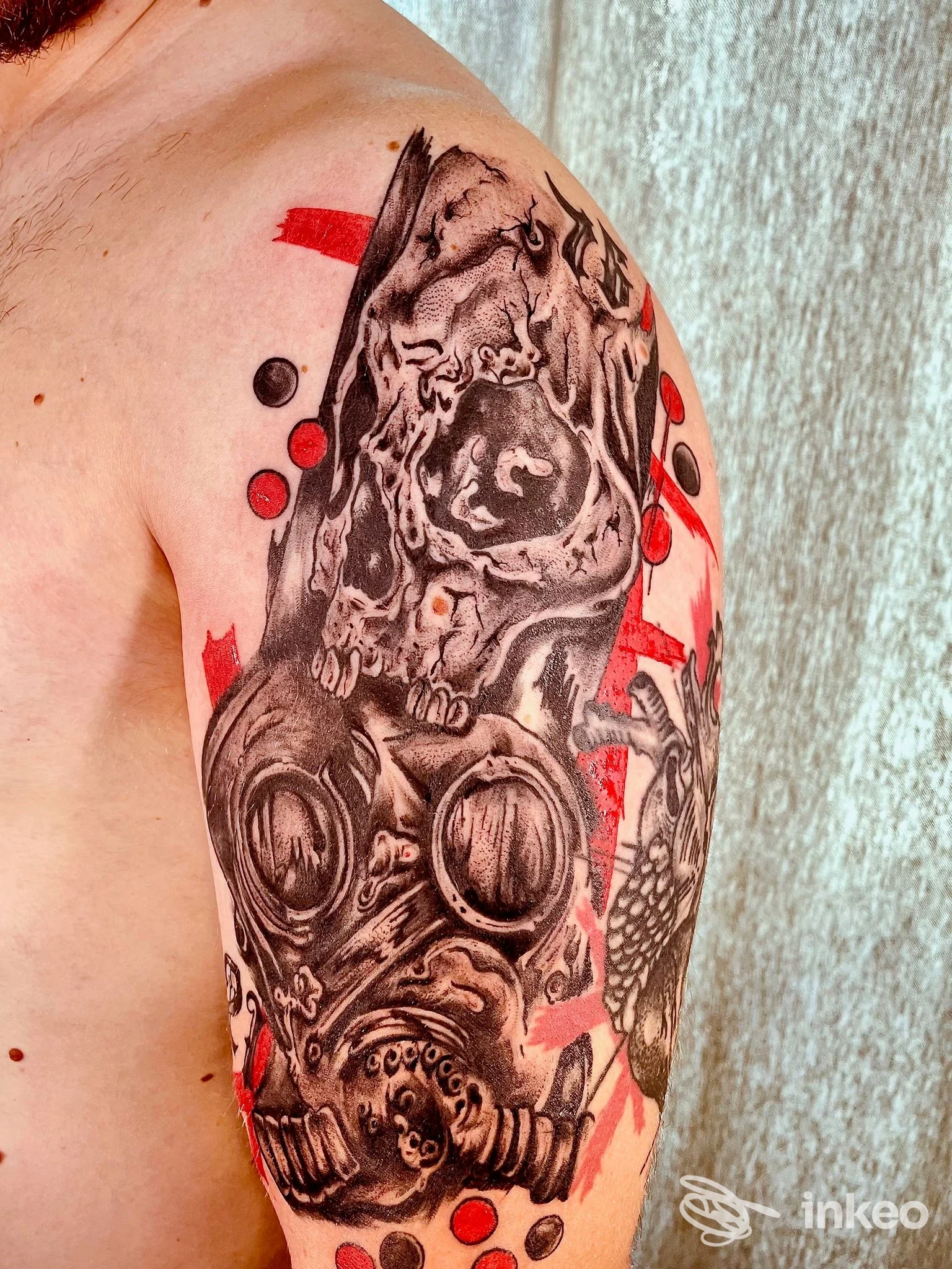 Tatuaggio su braccio e spalla realizzato da Old School Tattoo Family a Civitanova Marche raffigurante maschera antigas e teschio con elementi neri e rossi.