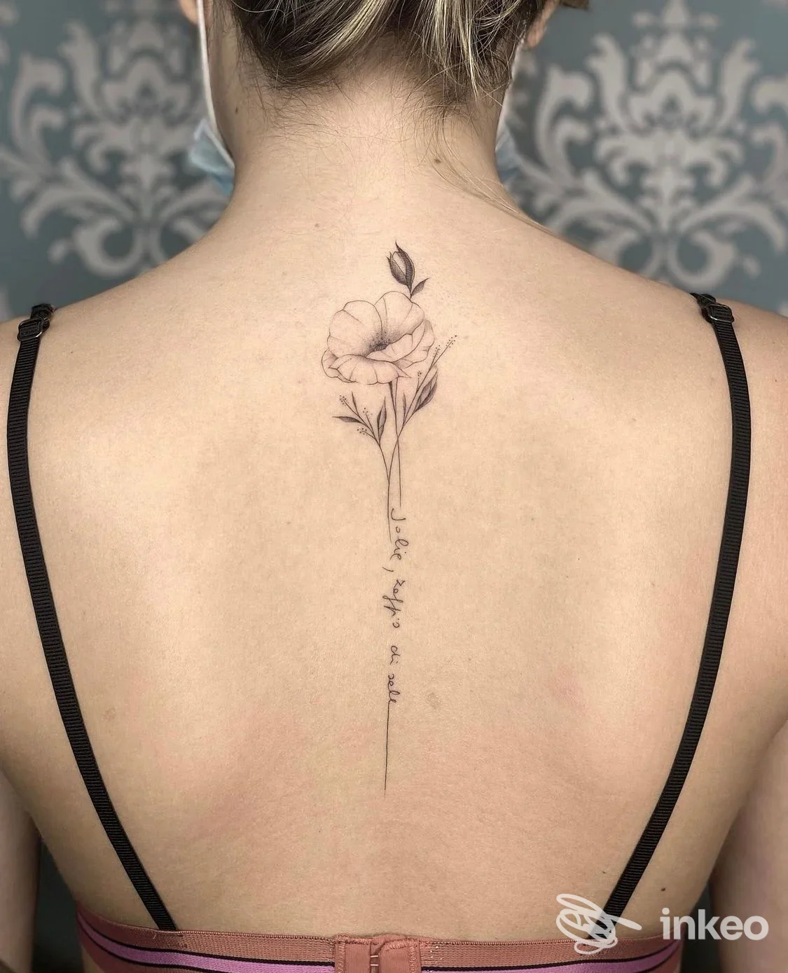 Tattoo floreale sottile lungo la schiena, disegno su pelle reale; visibile solo il dorso senza volto. Studio ICON Tattoo Studio non indicato.