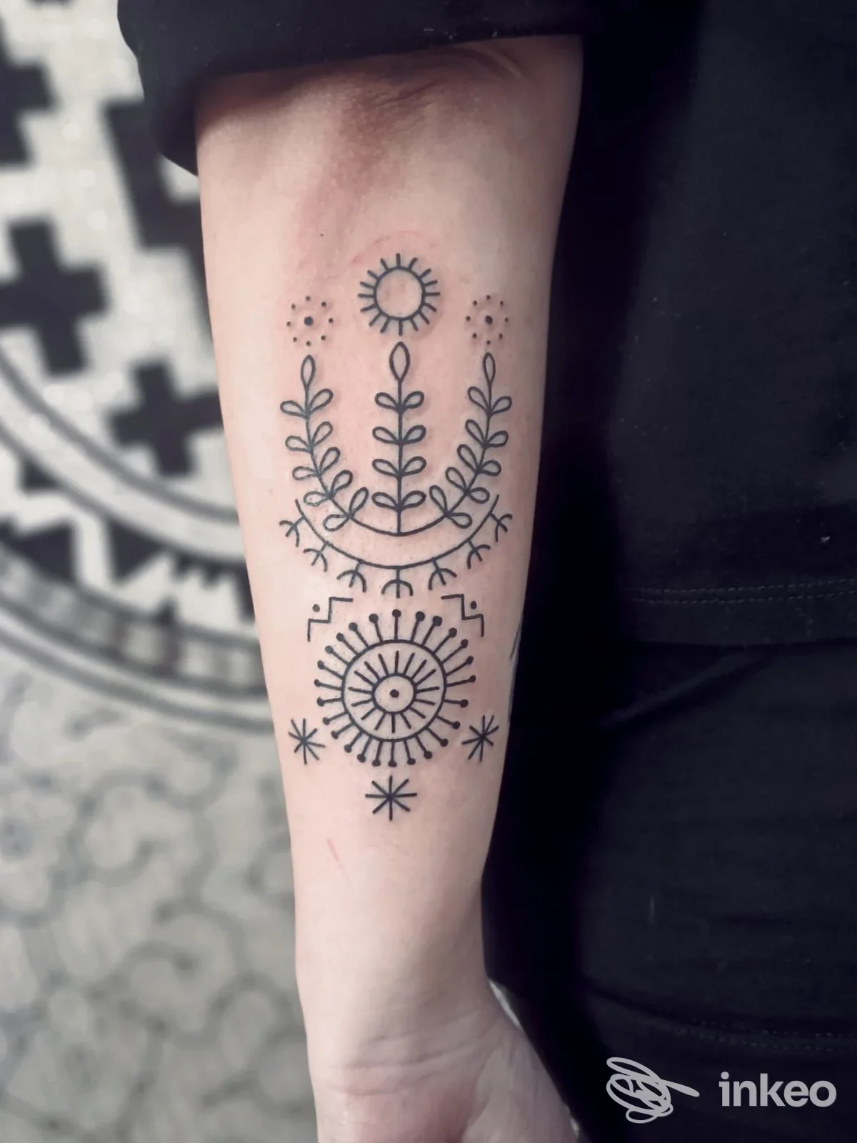Tatuaggio nero a linee e motivi botanici sull'avambraccio interno, fotografia di Pelle Bianca Tattoo a Senigallia.