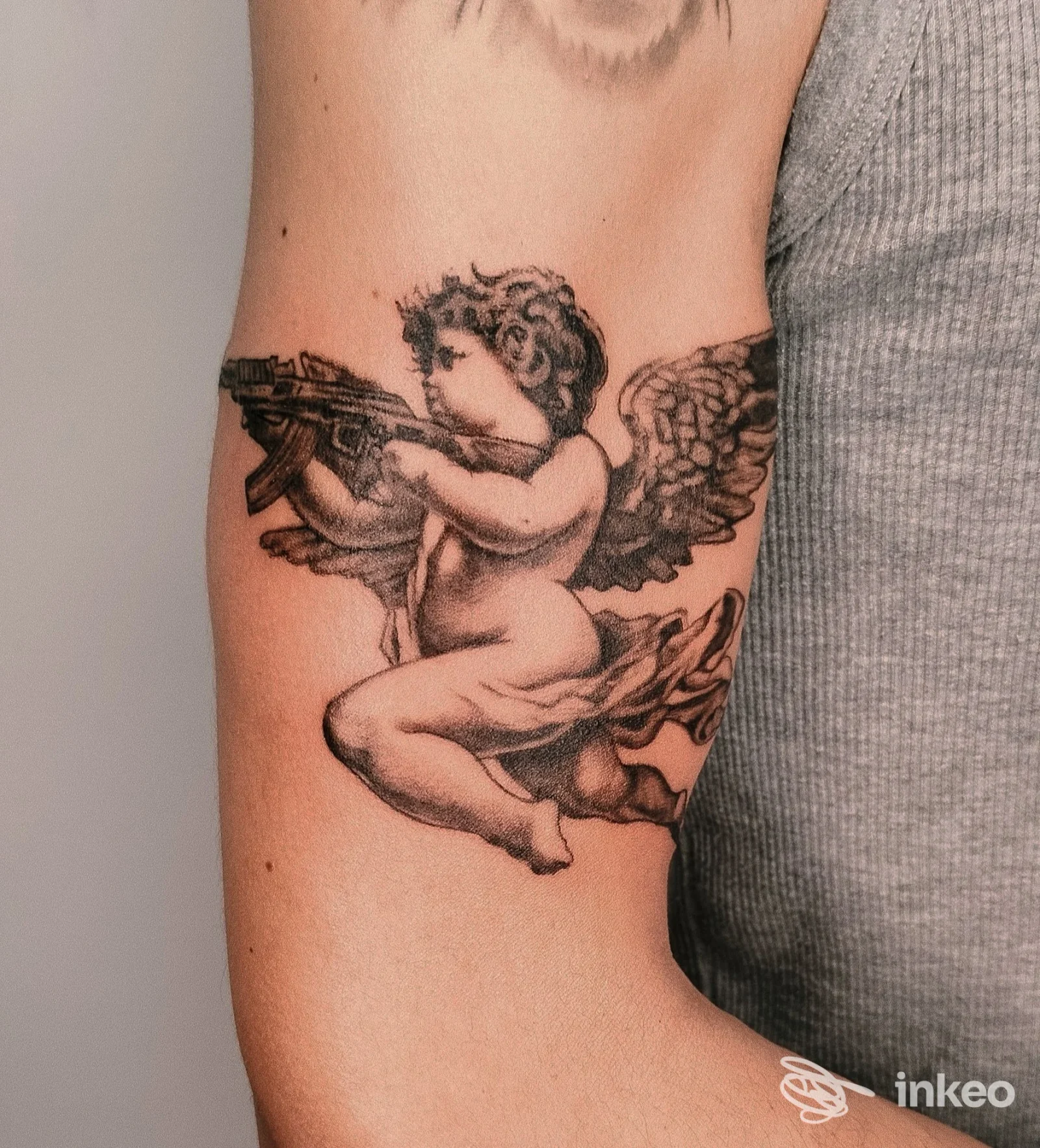 Tatuaggio in bianco e nero di un putto alato su braccio superiore, foto inviata da SETTANTA7 TATTOO STUDIO, Castelraimondo.