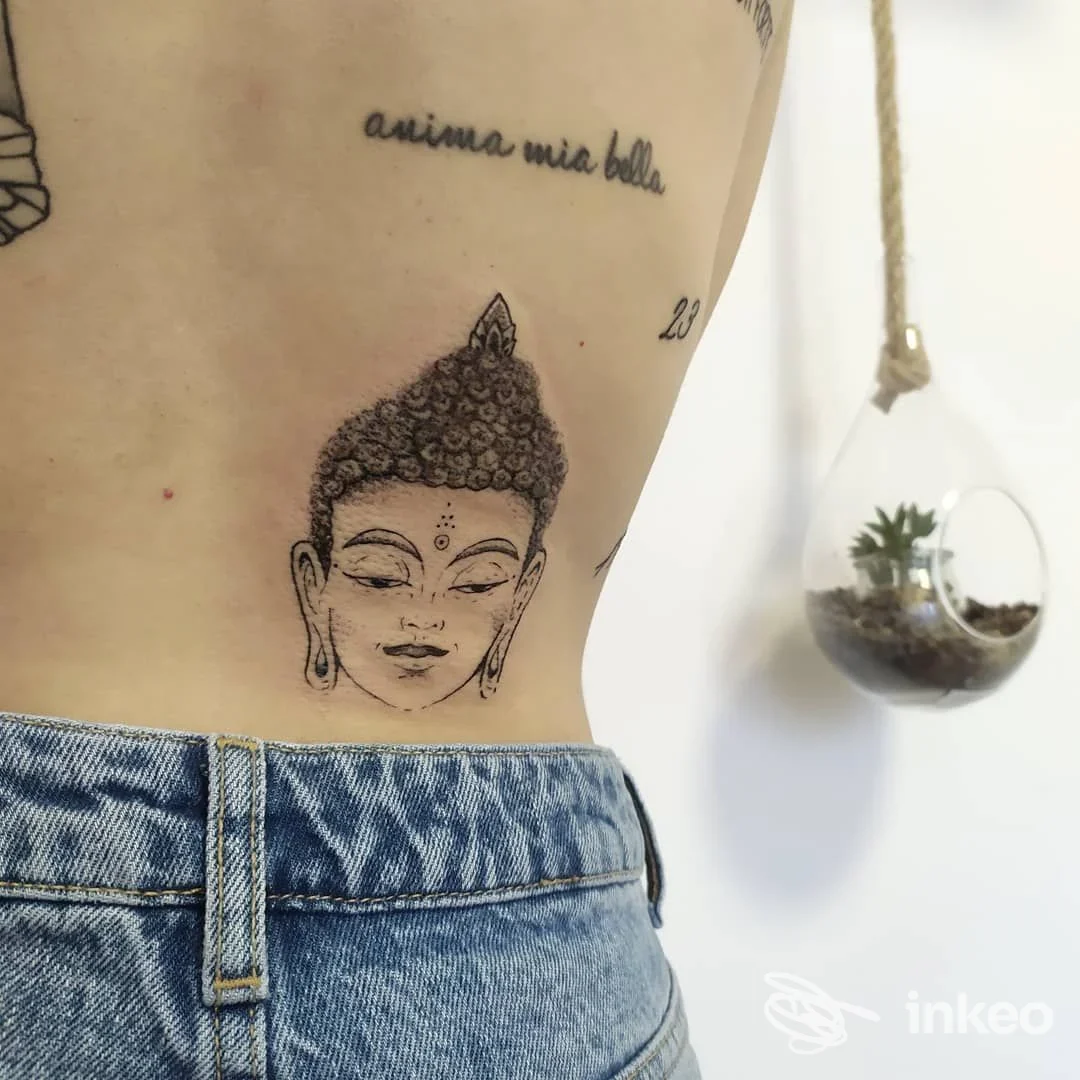 Tatuaggio a linework di un volto di Buddha sul fianco, immagine fornita da SIBILLA TATTOO ROOMS - Sforzacosta.