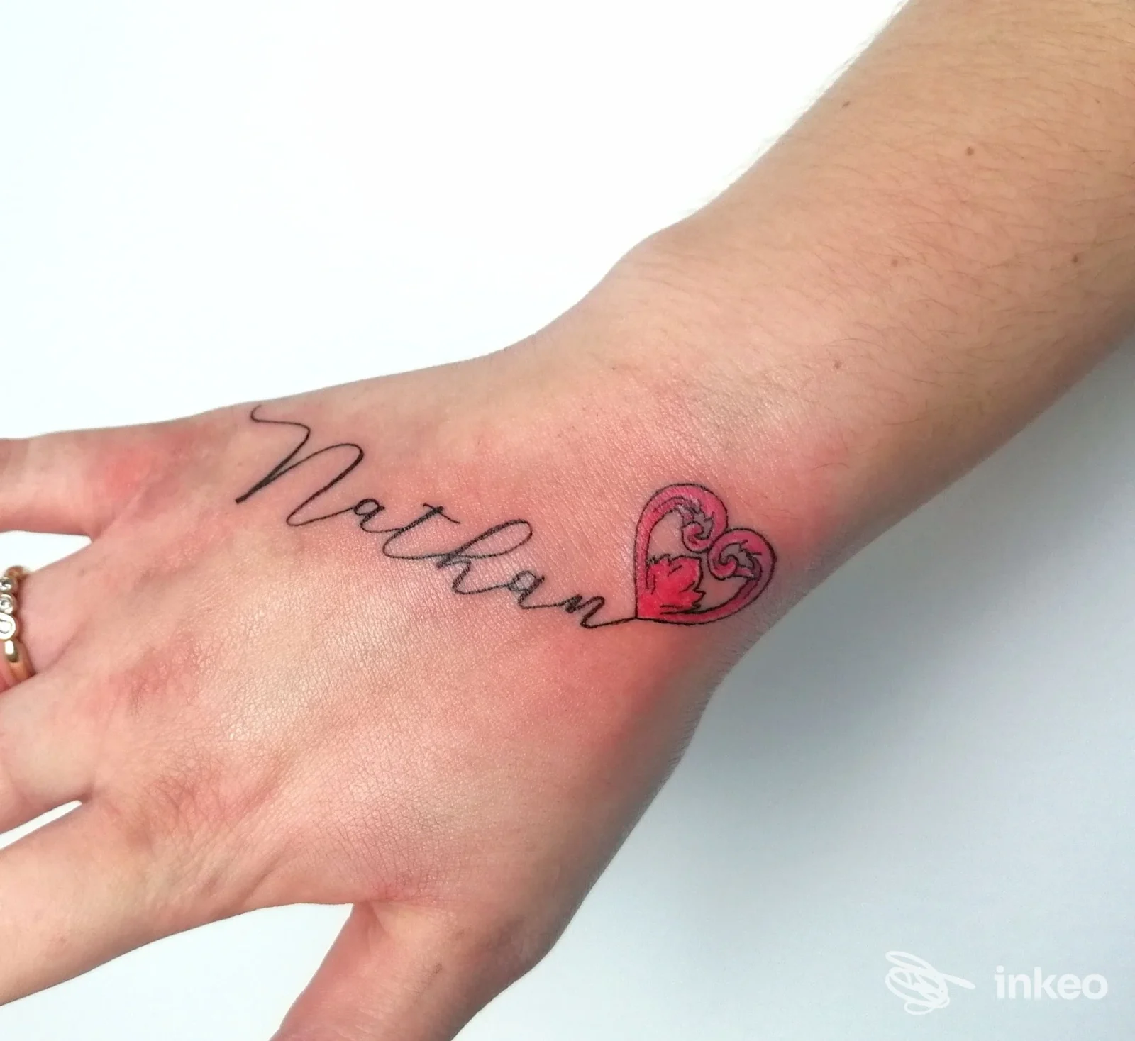 Tatuaggio sul dorso della mano con la scritta 'Nathan' e un cuore rosso, realizzato da STONE TATTOO a Sassoferrato.
