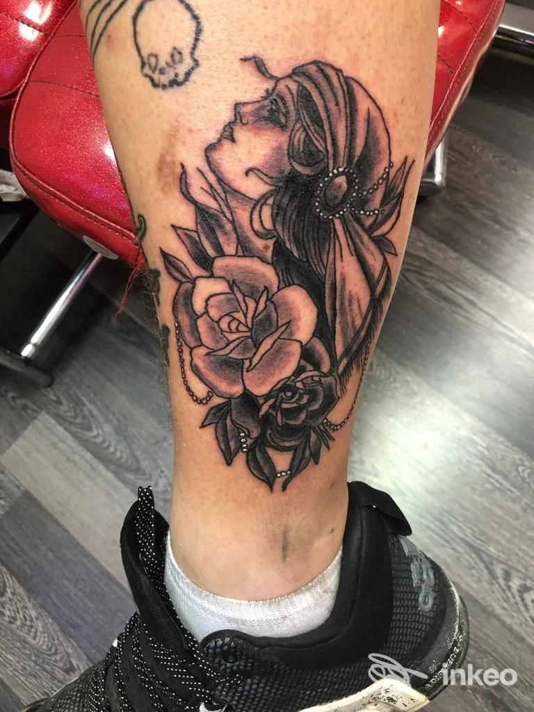Tatuaggio in bianco e nero su polpaccio con profilo femminile, perle e rose - Santeria Tattoo Studio, Chiaravalle.