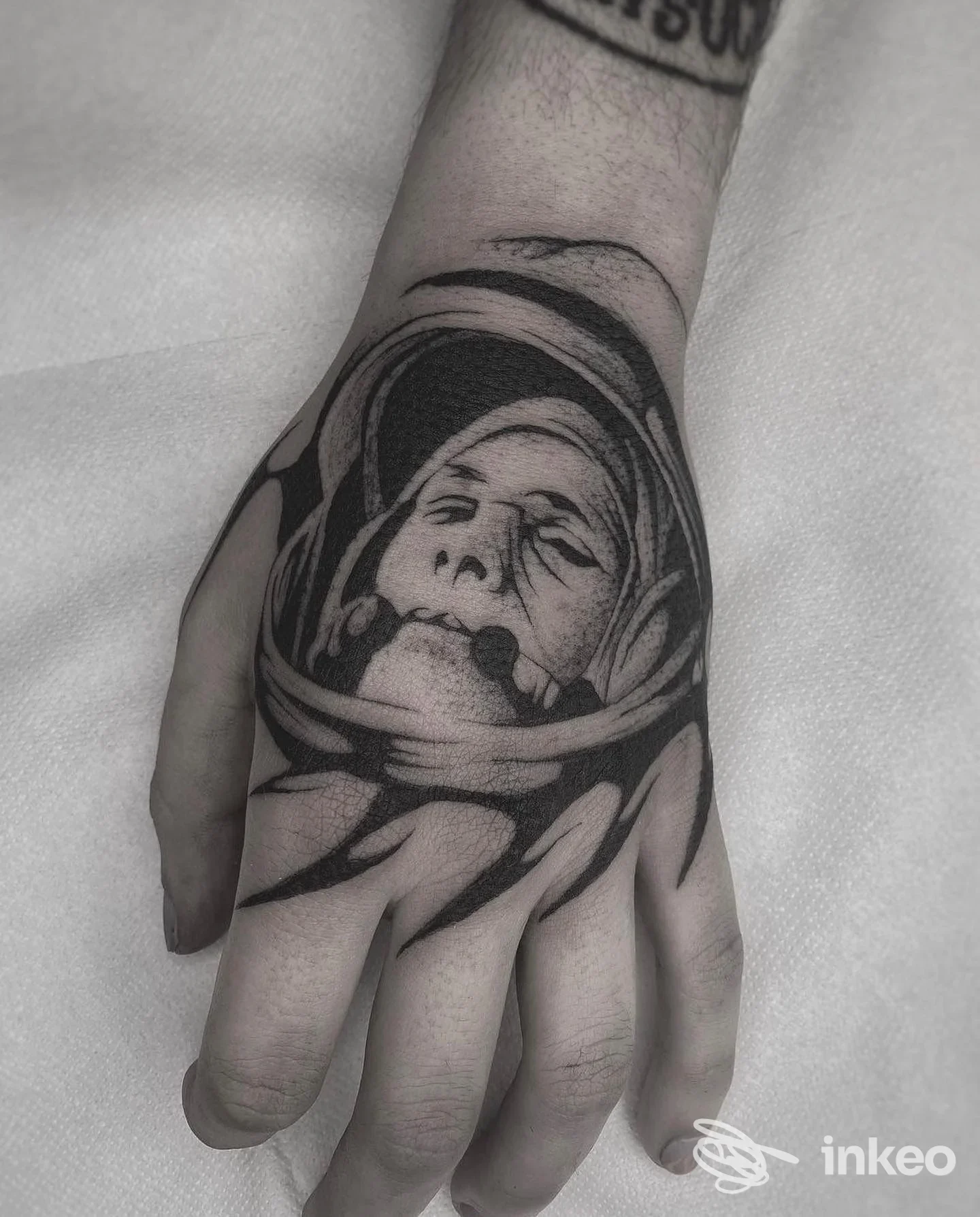 Tatuaggio blackwork sul dorso della mano realizzato da Stlkr Art & Tattoo a Fossombrone, ritratto di un astronauta/volto stilizzato in nero.