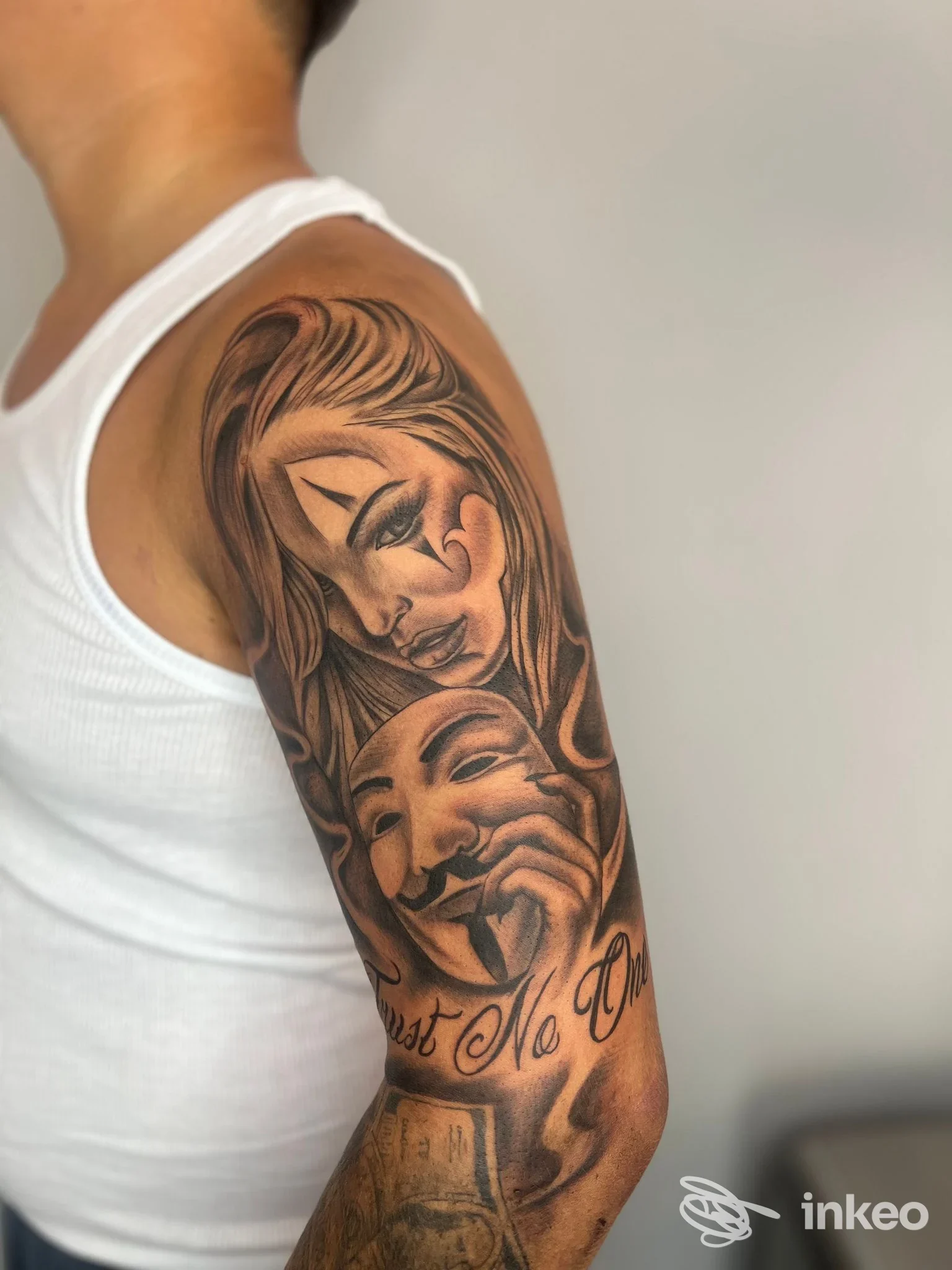 Mezza manica in bianco e nero sul braccio superiore con volti realistici; immagine del Simone Innamorati Tattoo Studio a San Benedetto del Tronto.