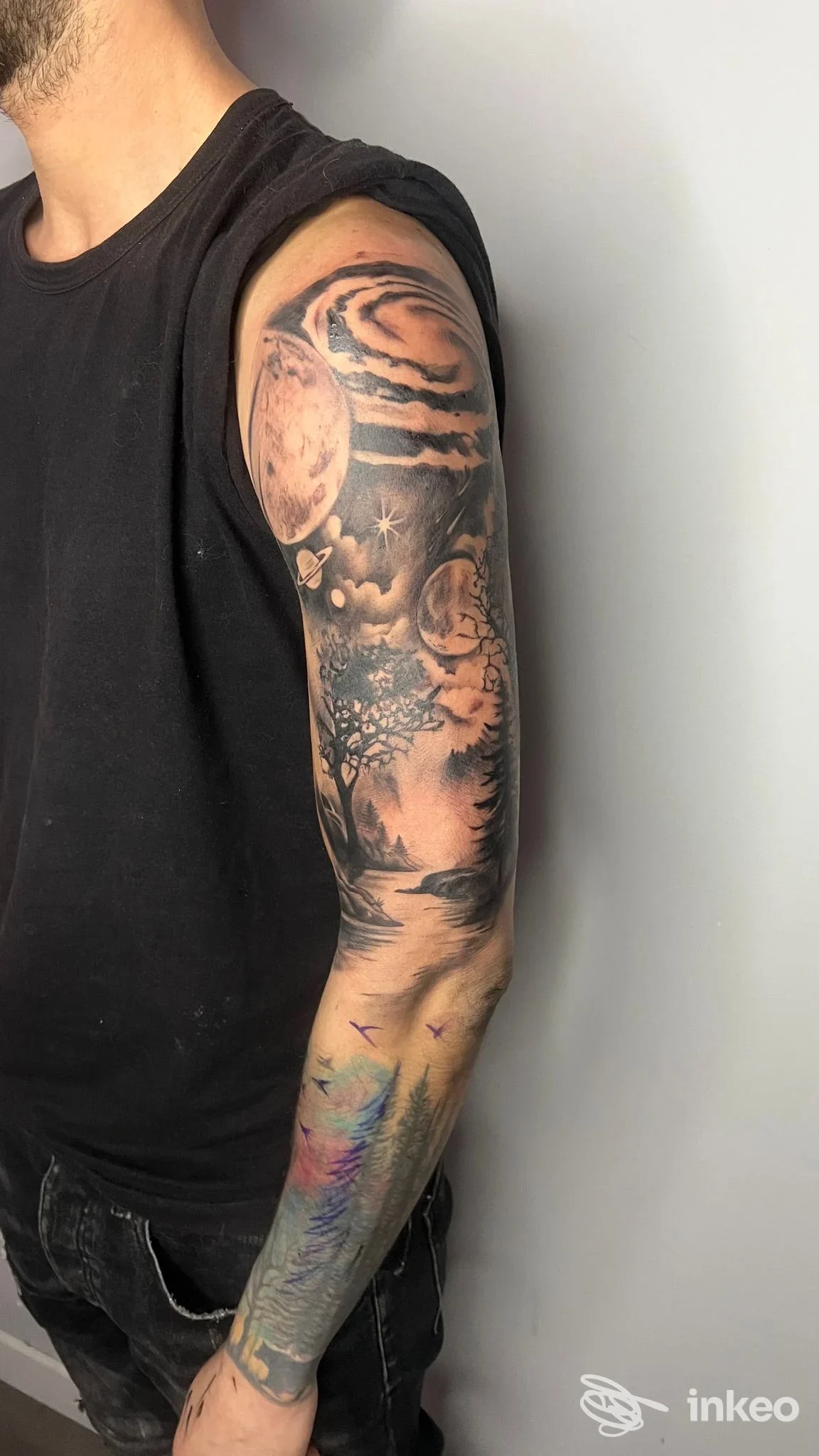 Manica tatuata su braccio maschile con scene spaziali e paesaggio, foto di Simone Innamorati Tattoo Studio, San Benedetto del Tronto.