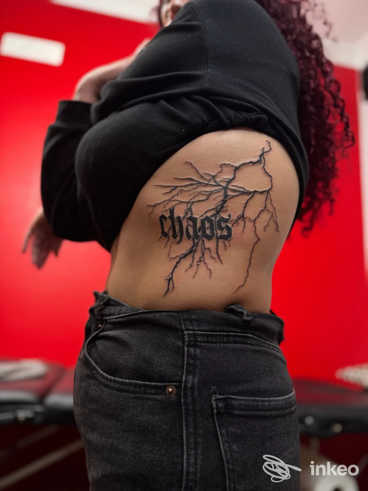 Tatuaggio lettering "chaos" con ramificazioni nere sul fianco, foto dallo studio Starskcream Tattoo ad Ancona.