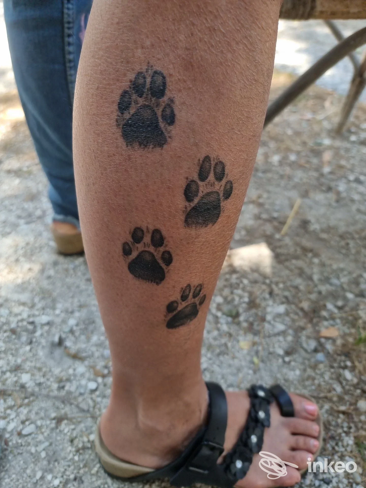 Impronte di zampe tatuate in nero sul polpaccio, foto per Tattoo Lion Flowers Pesaro, Pesaro.