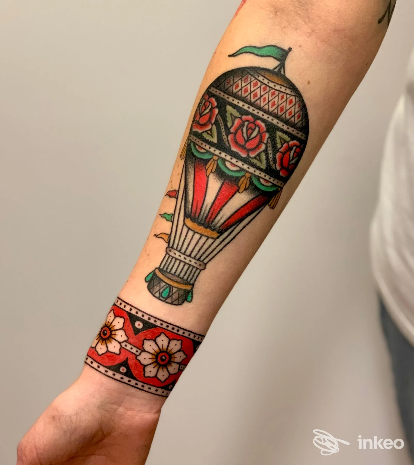 Avambraccio con tatuaggio tradizionale a forma di mongolfiera e banda floreale, lavoro di Tattooing Room a Appignano.