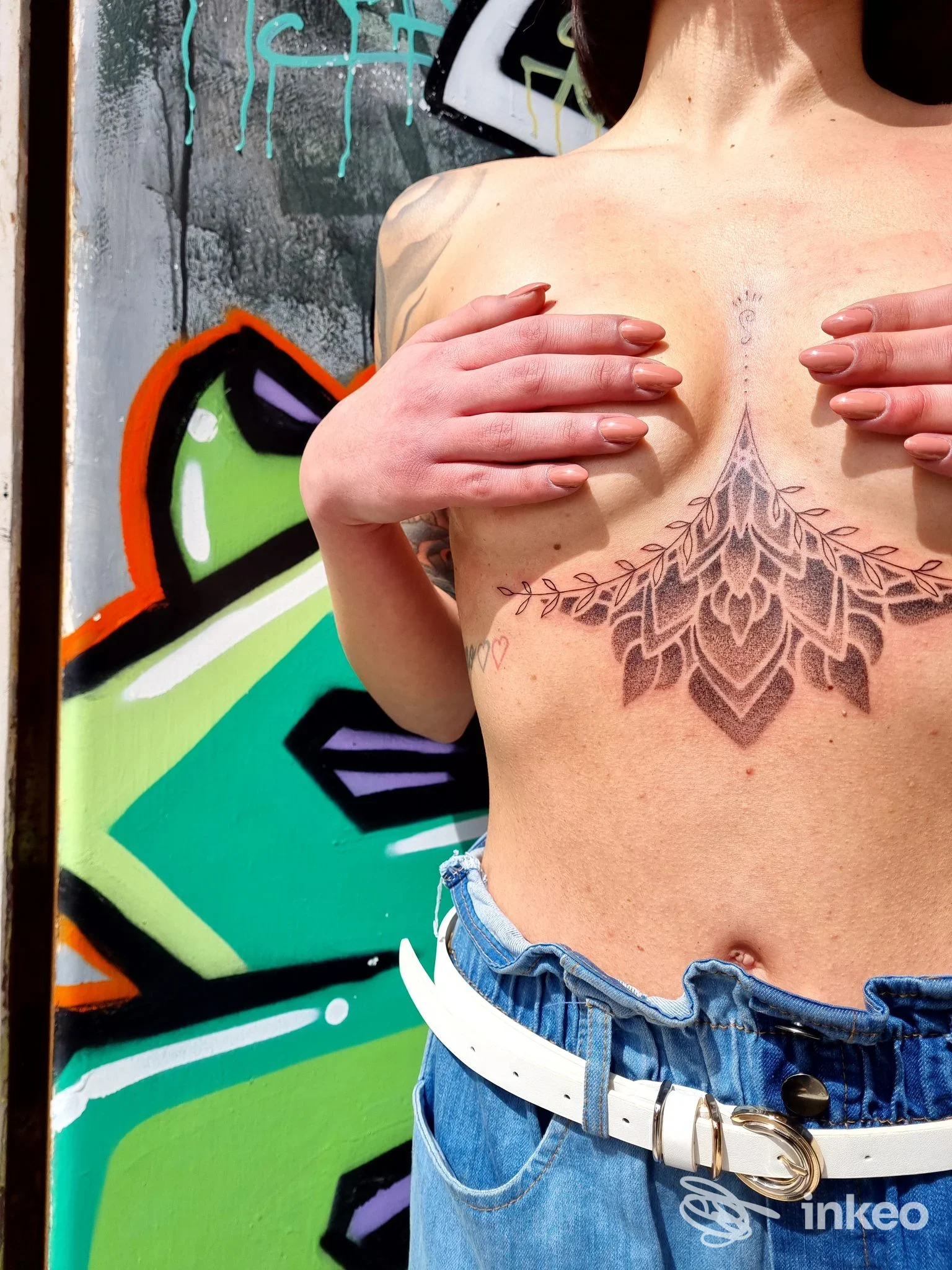 Tatuaggio ornamentale centrale sullo sterno, foto di Unknown Artist - Tattoo Studio & Piercing a Porto Recanati, primo piano torso con sfondo murale.