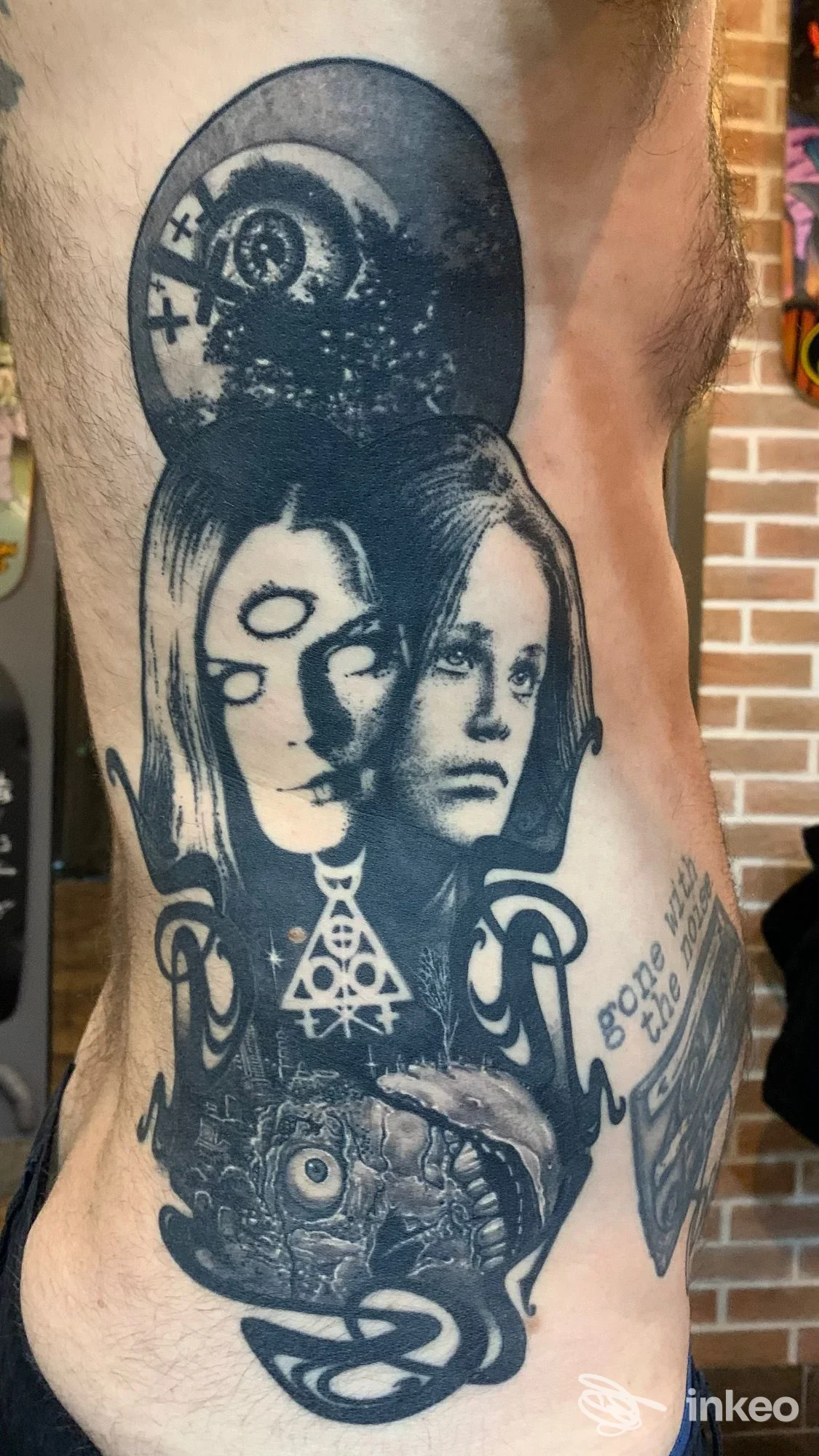 Grande tatuaggio nero a tutta superficie sul fianco con volti sovrapposti e simboli, Vincent Bertrand Tattoo, Porto San Giorgio.