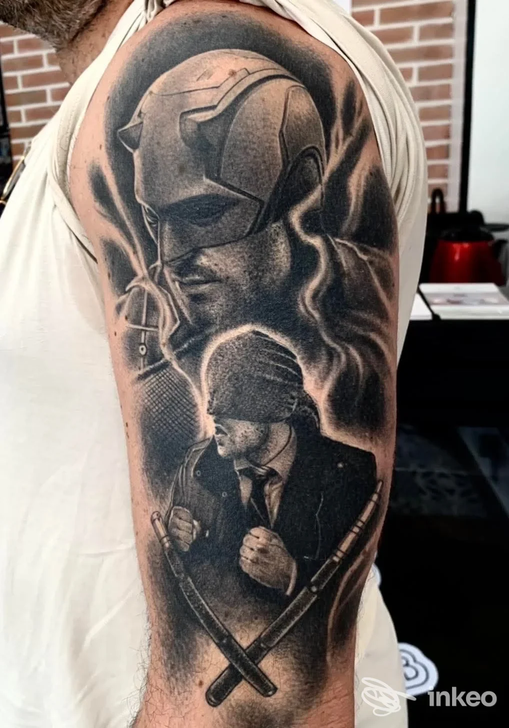 Grande tatuaggio realistico black & grey sull'alto braccio con figure maschili; immagine fornita da Vincent Bertrand Tattoo, Porto San Giorgio.