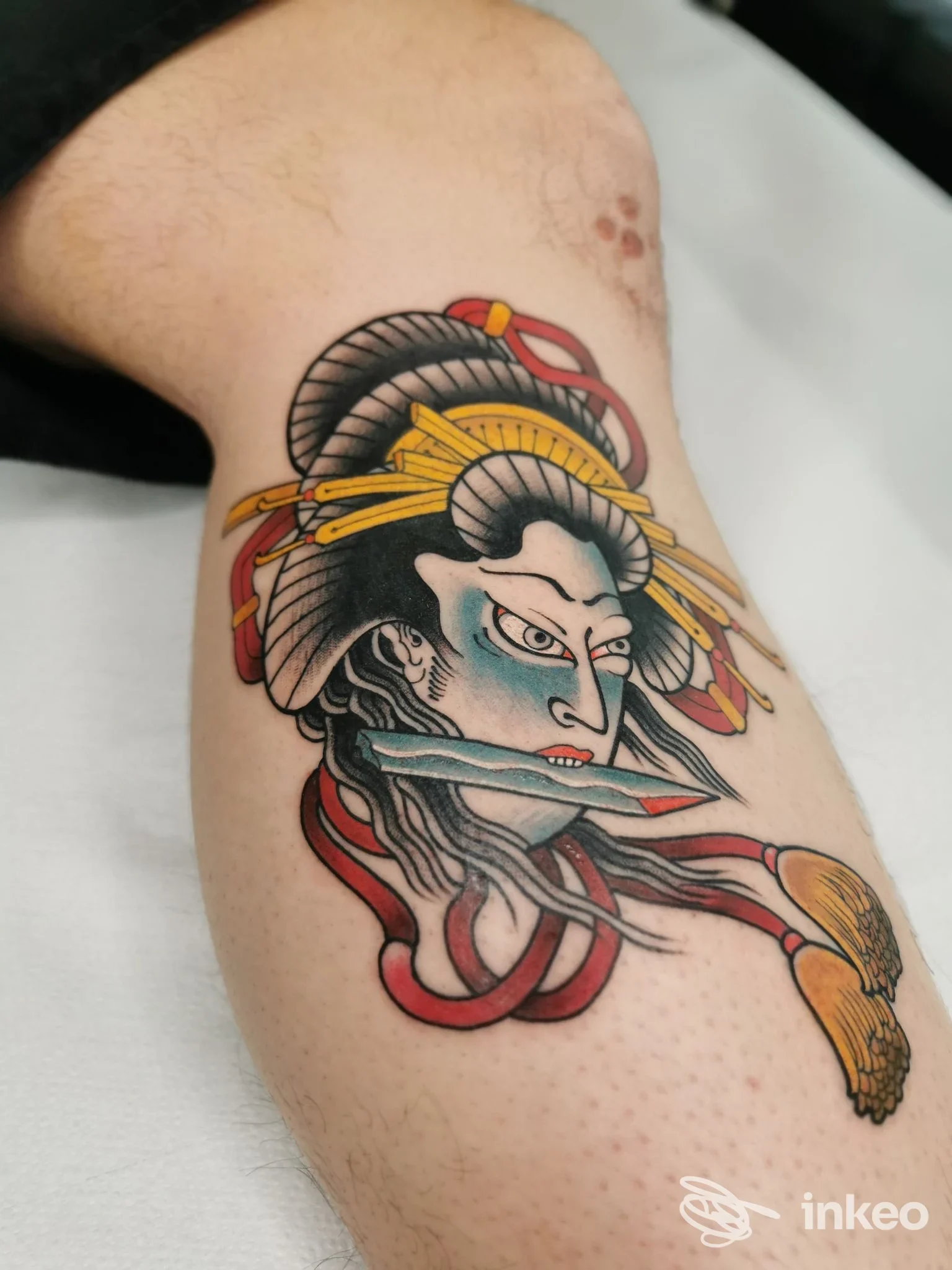 Tatuaggio colorato su polpaccio con volto stilizzato, pugnale e nastri — Williams Tattoo, Fano.