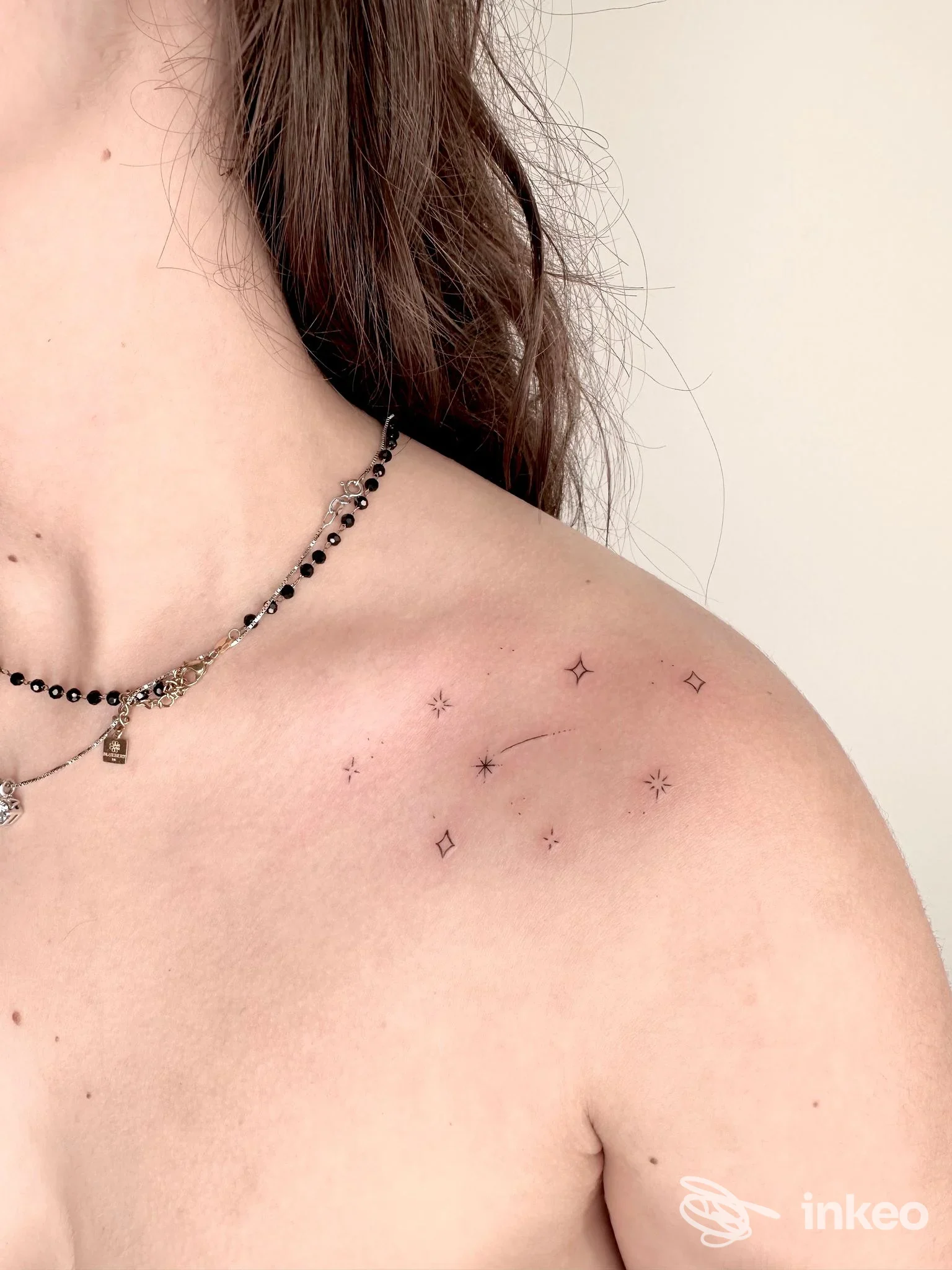 Primo piano di spalla con piccolo tatuaggio minimal di stelline e rombi, foto inviata da Velvet Tattoo Studio a Passo di Treia.