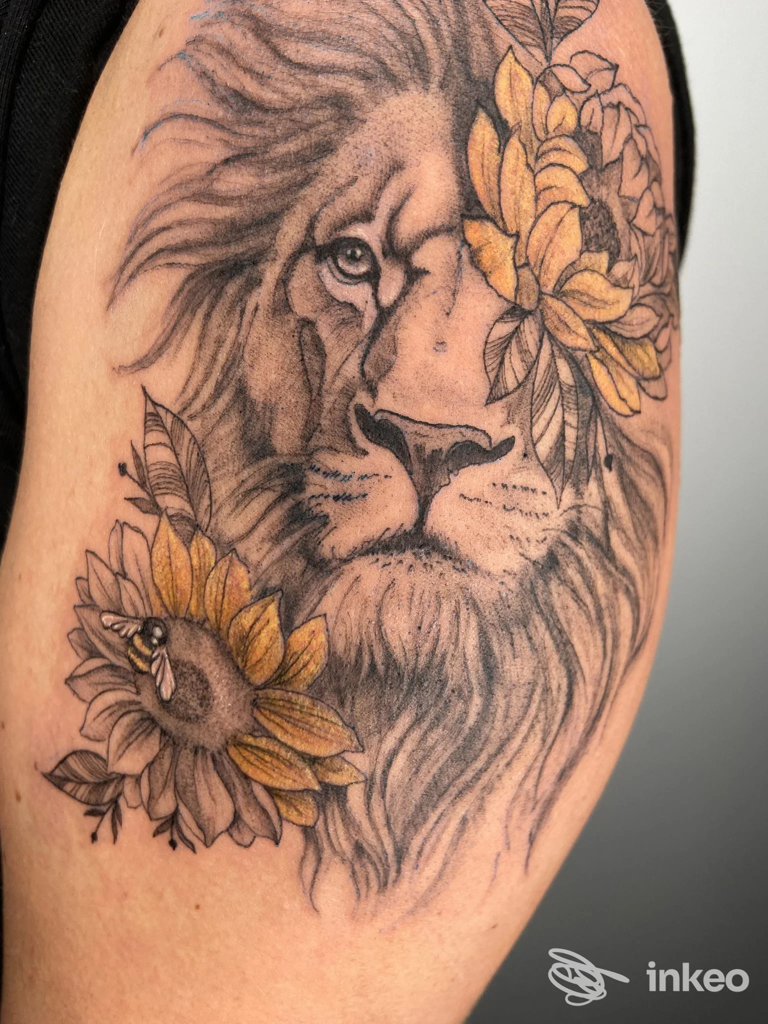 Tatuaggio di leone con fiori sul braccio, realizzato da Velvet Tattoo Studio a Passo di Treia.