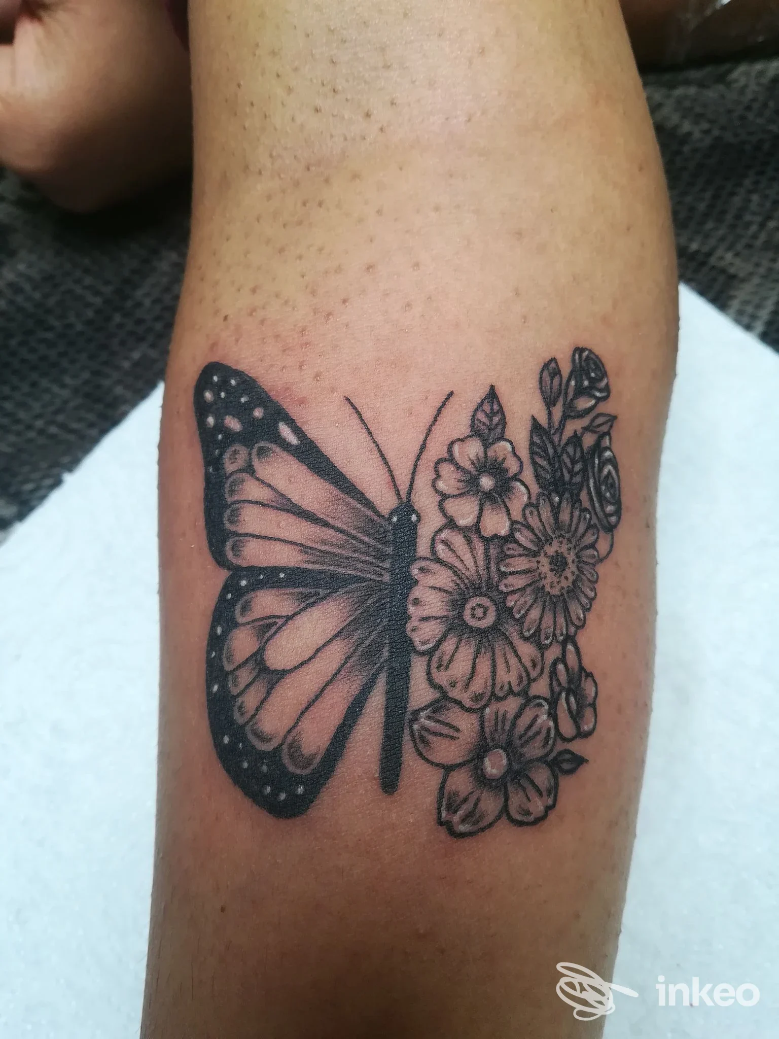 Tatuaggio bianco e nero a farfalla e fiori sull'avambraccio, Zoe Tattoo Studio, Macerata.