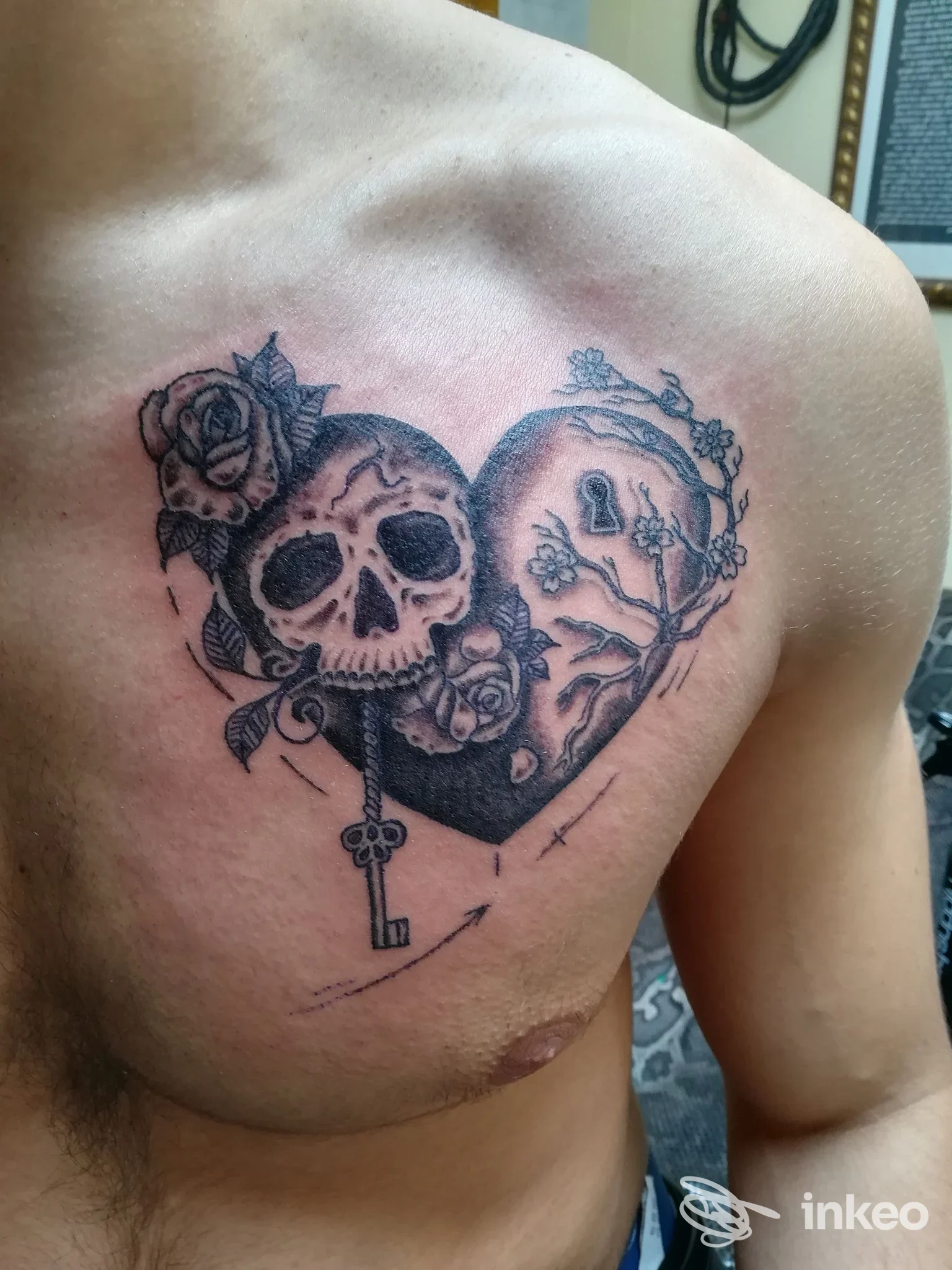 Tatuaggio a cuore con teschio, rose e chiave sul petto sinistro realizzato da Zoe Tattoo Studio, Macerata.