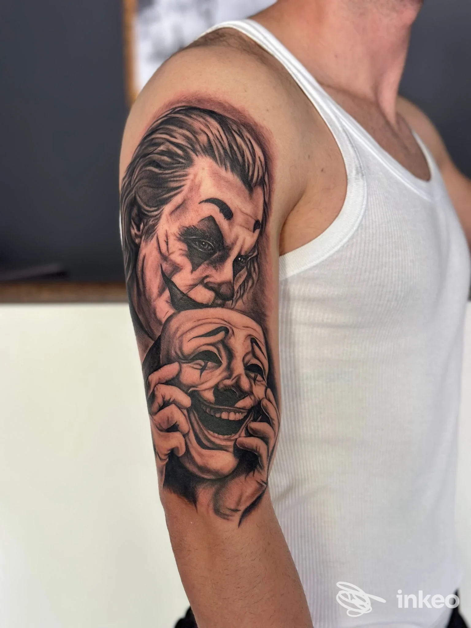 Tatuaggio realistico in bianco e nero sul braccio superiore con due volti; immagine fornita da Acanthus Tattoo Studio, Isernia.