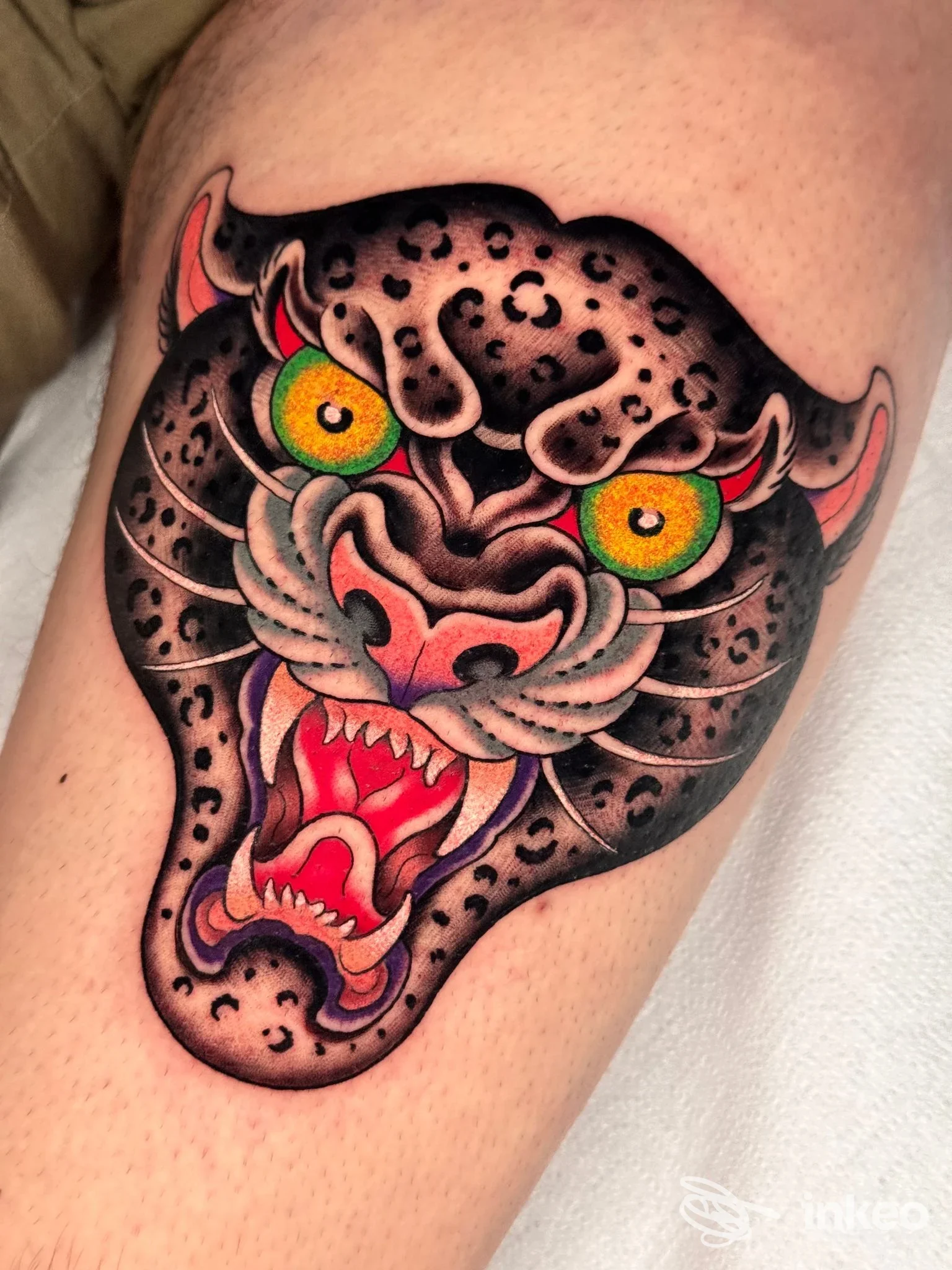 Tatuaggio colorato a forma di testa di pantera sulla coscia, contorni neri e occhi giallo-verdi. Foto Lone Tower tattoo parlour, Campobasso.