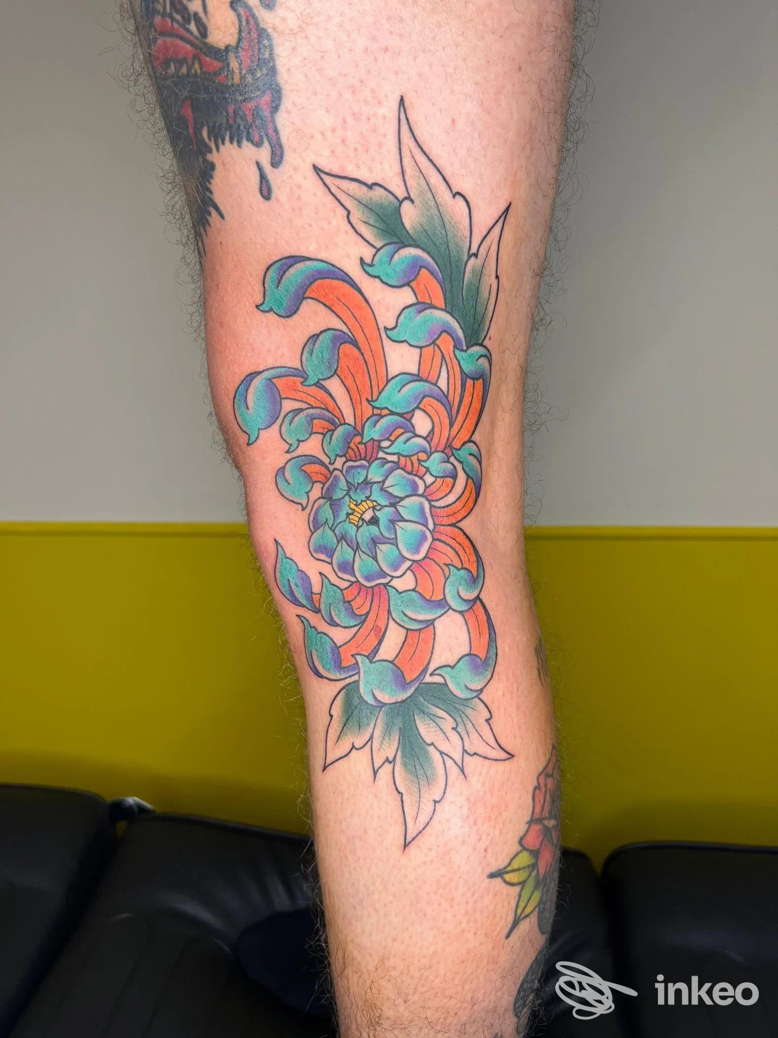 Tatuaggio floreale su polpaccio realizzato da Lone Tower tattoo parlour, Campobasso: composizione colorata in turchese, arancio e verde.