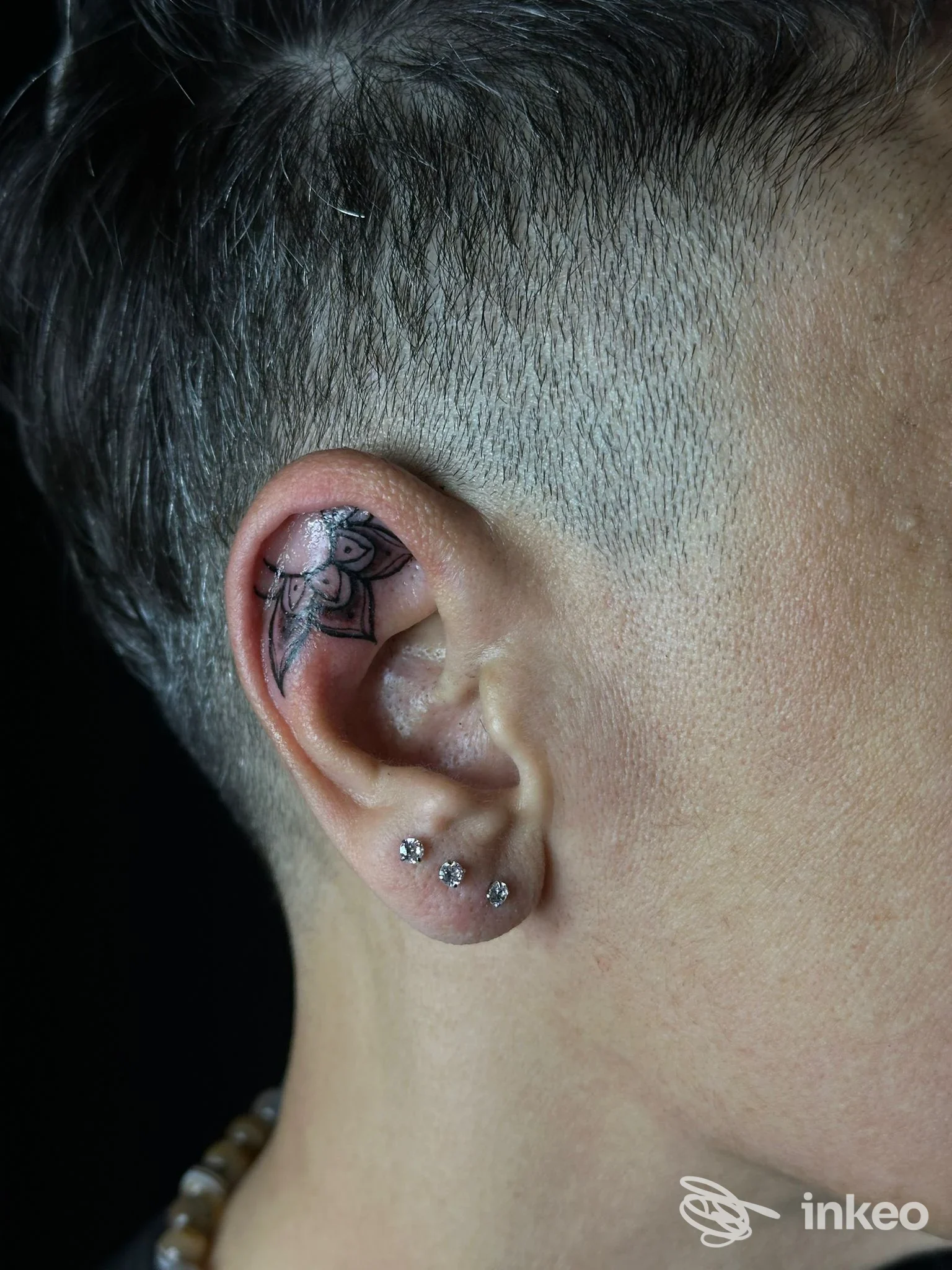 Tatuaggio floreale nell'antelice dell'orecchio in primo piano, scatto laterale; 17 Tattoo Studio, Torino.