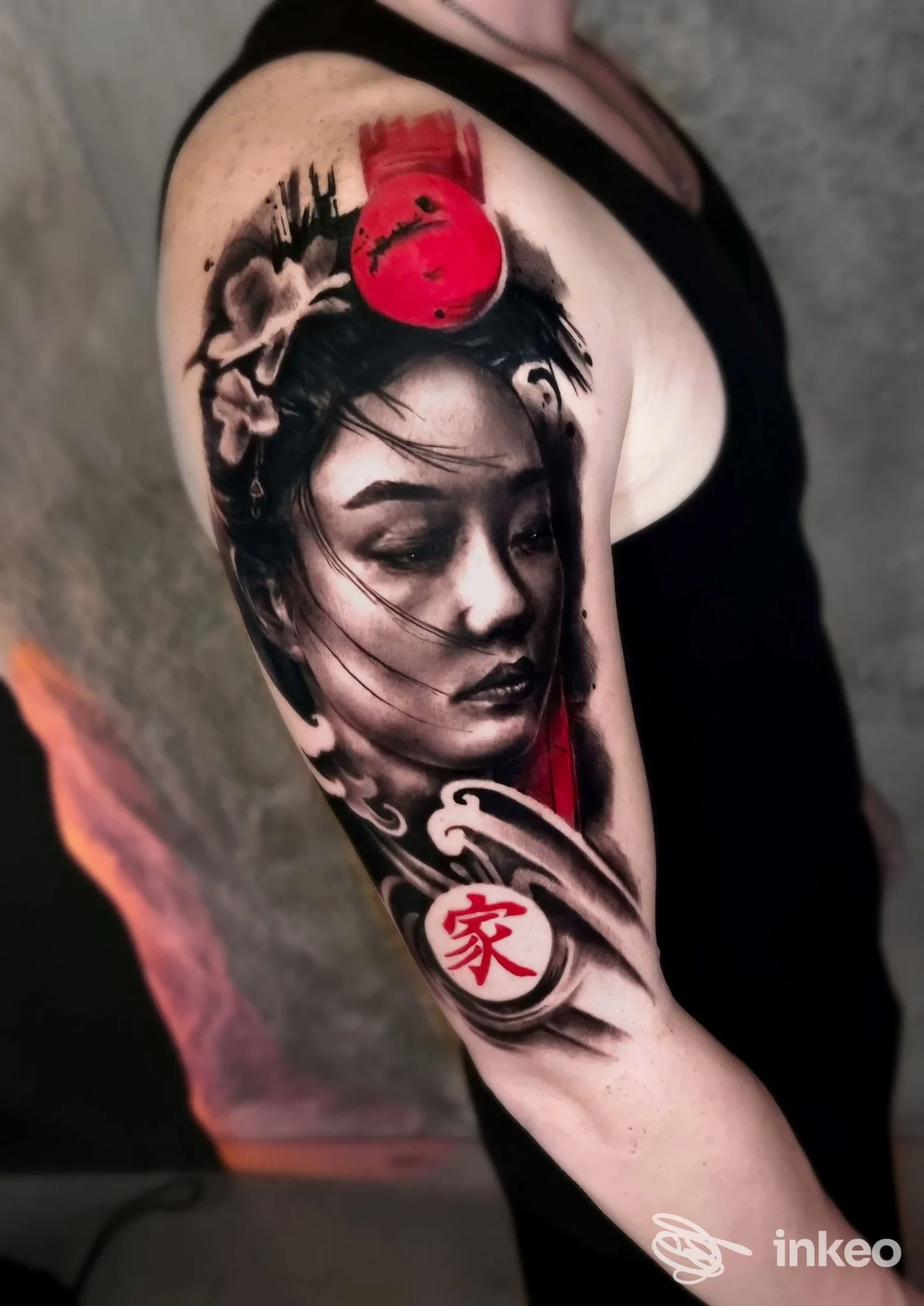 Grande tatuaggio realistico sul braccio superiore con ritratto femminile e accenti rossi, 24 Tattoo Studio Carmagnola, Carmagnola.