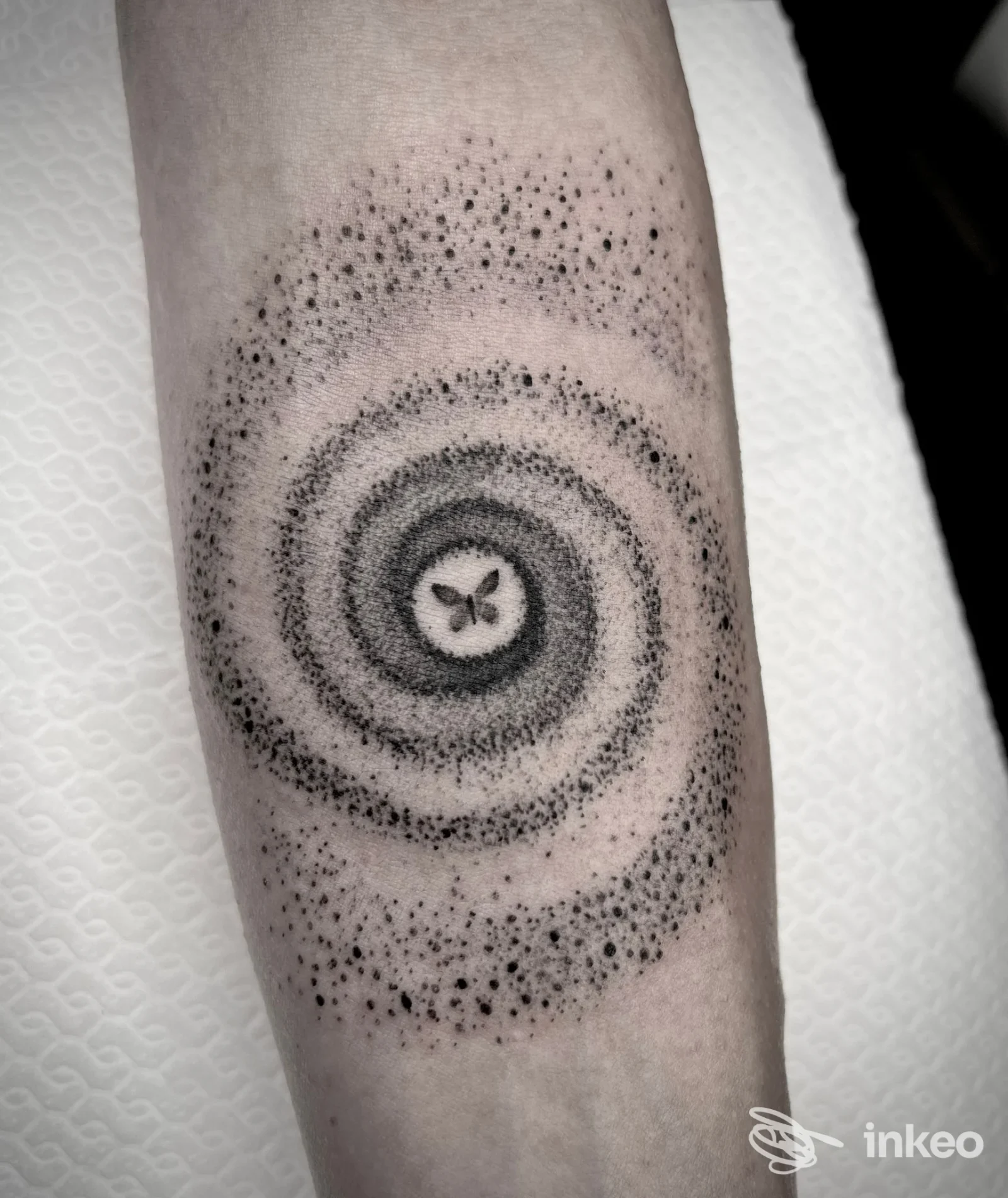 Tatuaggio dotwork a spirale con piccola farfalla al centro sull'avambraccio, foto inviata da Aline Blanc Tattoo Shop, Torino.