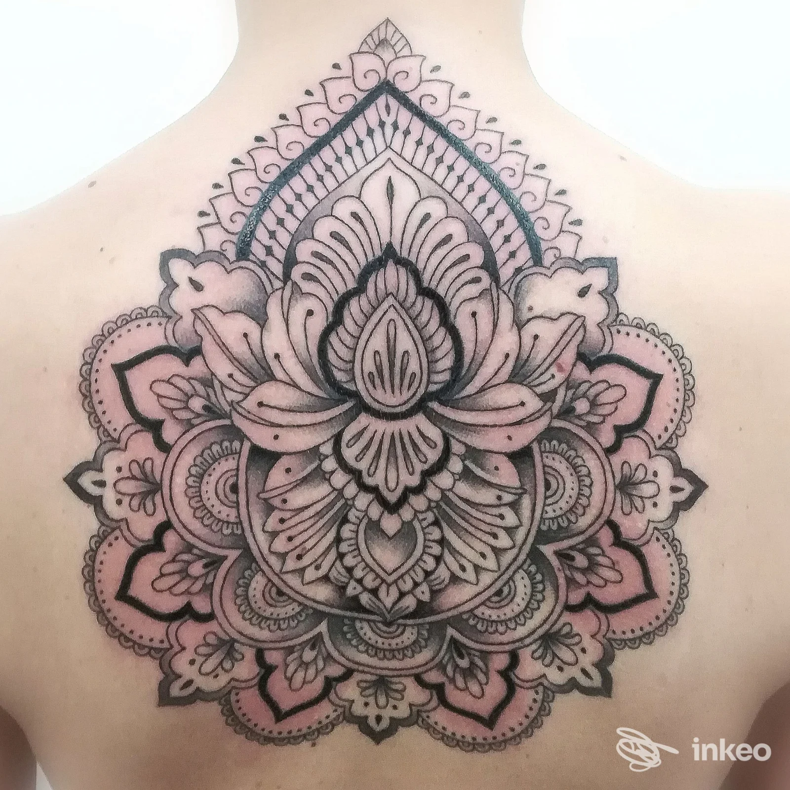 Grande tatuaggio mandala ornamentale sul dorso superiore, dettagli puntinati e sfumature rosa, realizzato da Ainos Tattoo a Torino.