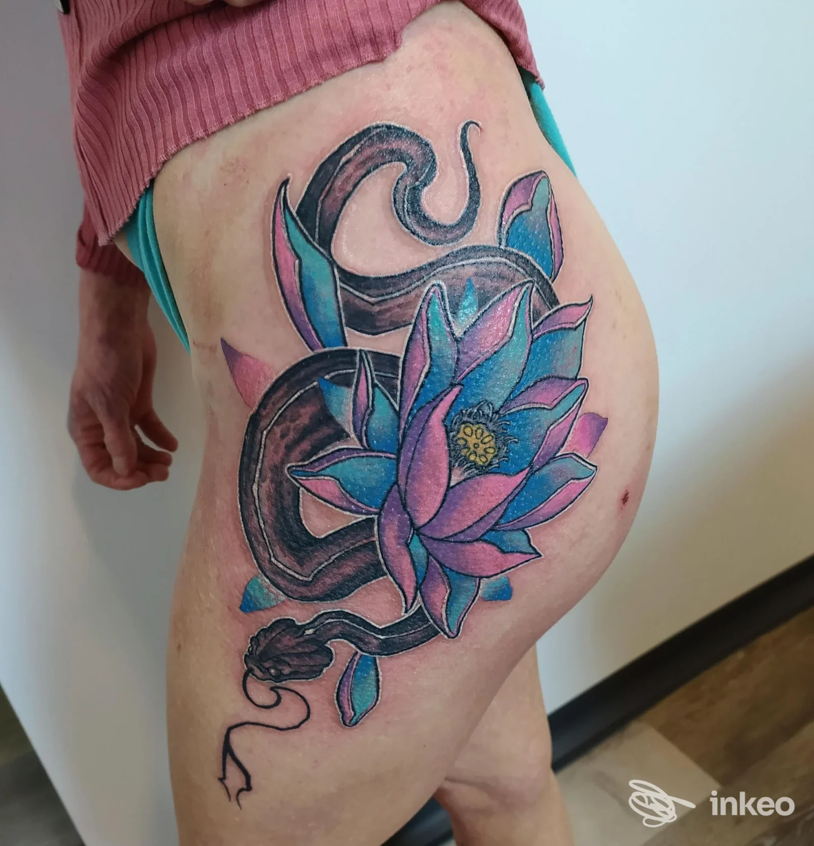Grande tatuaggio su fianco e coscia con serpente e fiore colorato, fotografato presso Al 3 tattoo studio a Biella.