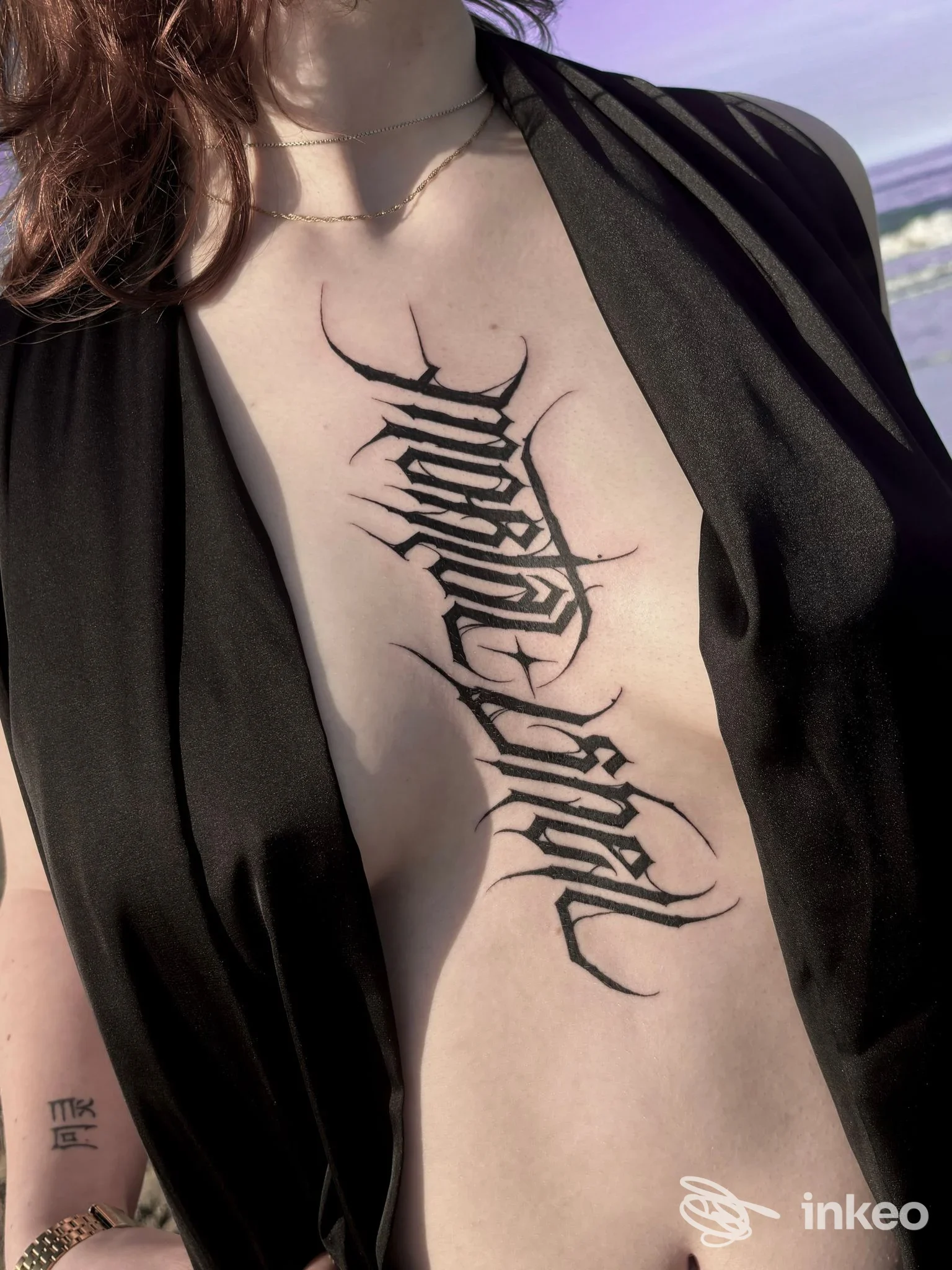 Primo piano del torace con grande tatuaggio calligrafico verticale; immagine fornita da Amanita Tattoo & piercing Torino, Torino.