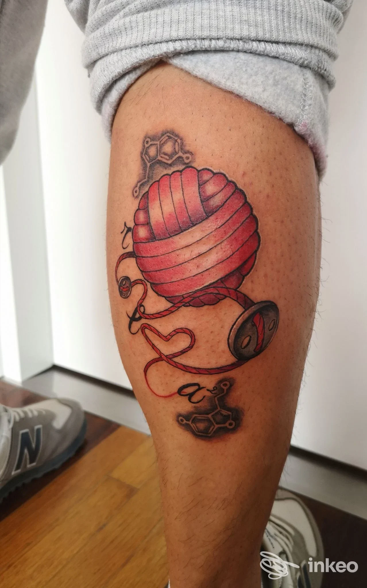 Tatuaggio su polpaccio raffigurante una matassina di lana rossa con filo, scatto fornito da Be Art tattoo, Bistagno.