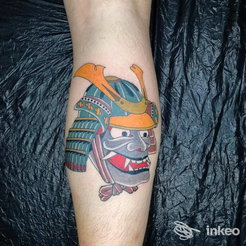 Tatuaggio maschera samurai colorata sul polpaccio, realizzato da Becchi Tattoo Cluster Studio a Torino.