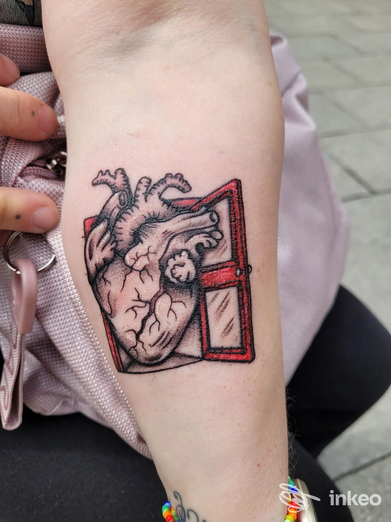 Tatuaggio su avambraccio con cuore anatomico e una finestra bordata di rosso, immagine fornita da Blink Studio Tattoo, Torino.