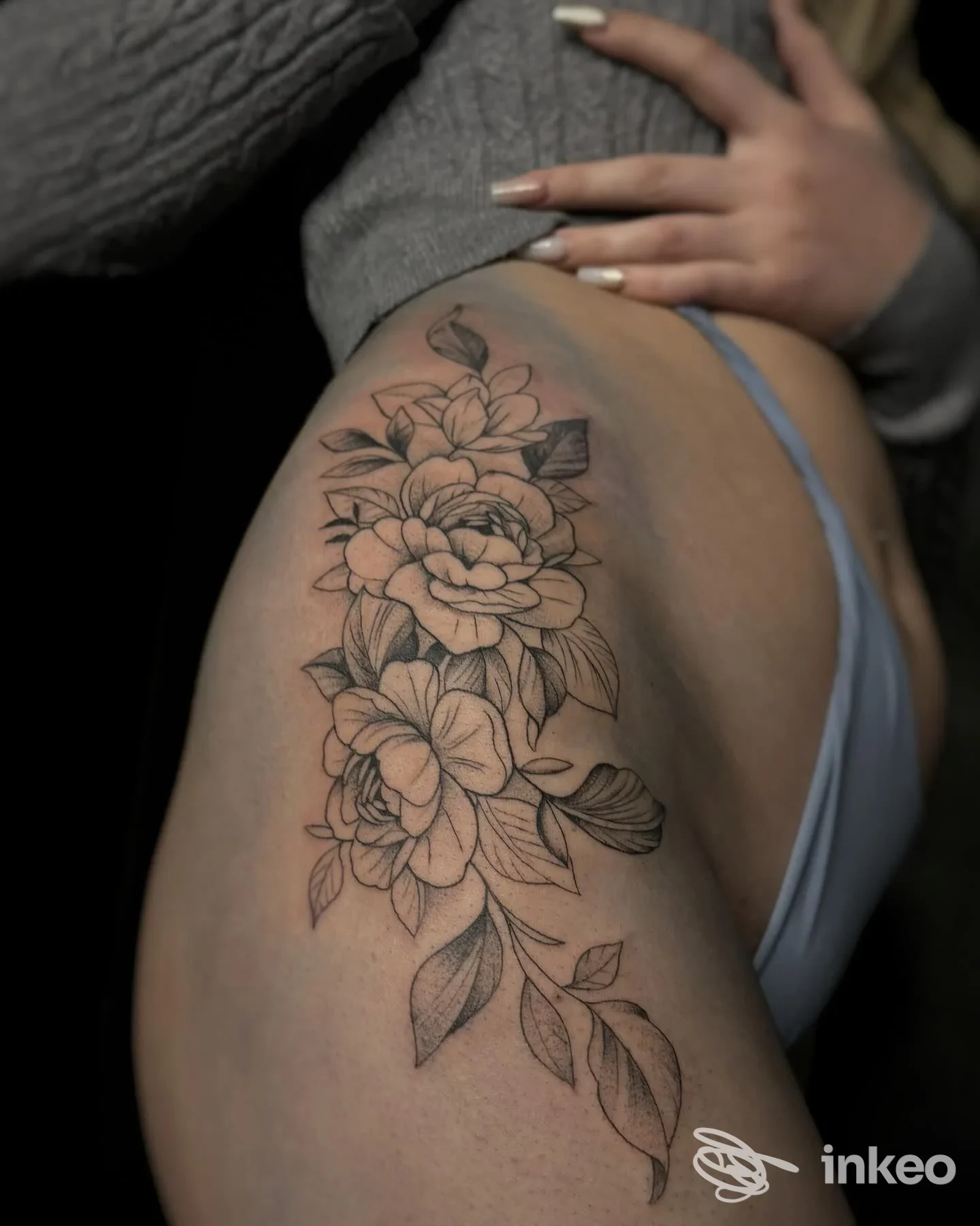 Tatuaggio floreale in bianco e nero sulla coscia, lavoro mostrato da Black Studio Tattoo & Piercing, Torino.