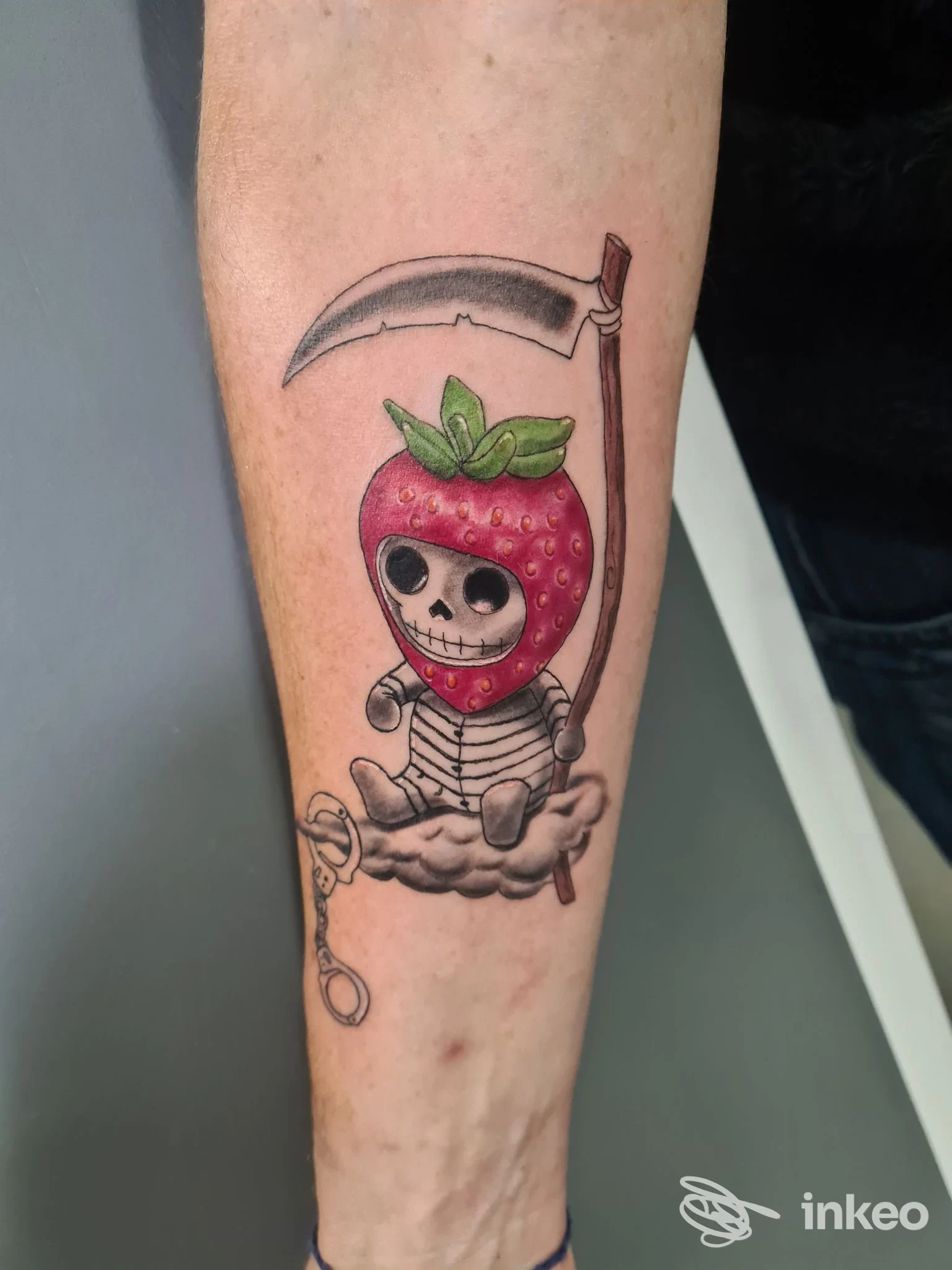Tatuaggio su avambraccio: personaggio scheletrico con testa a fragola e falce, Bogia Nen!! Tattoo, Condove.