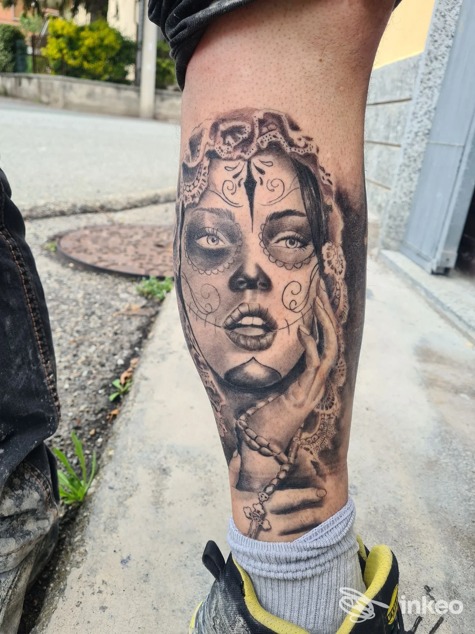 Tatuaggio realistico in bianco e nero raffigurante un volto femminile 'sugar skull' con mano e rosario sul polpaccio, Bogia Nen!! Tattoo, Condove.