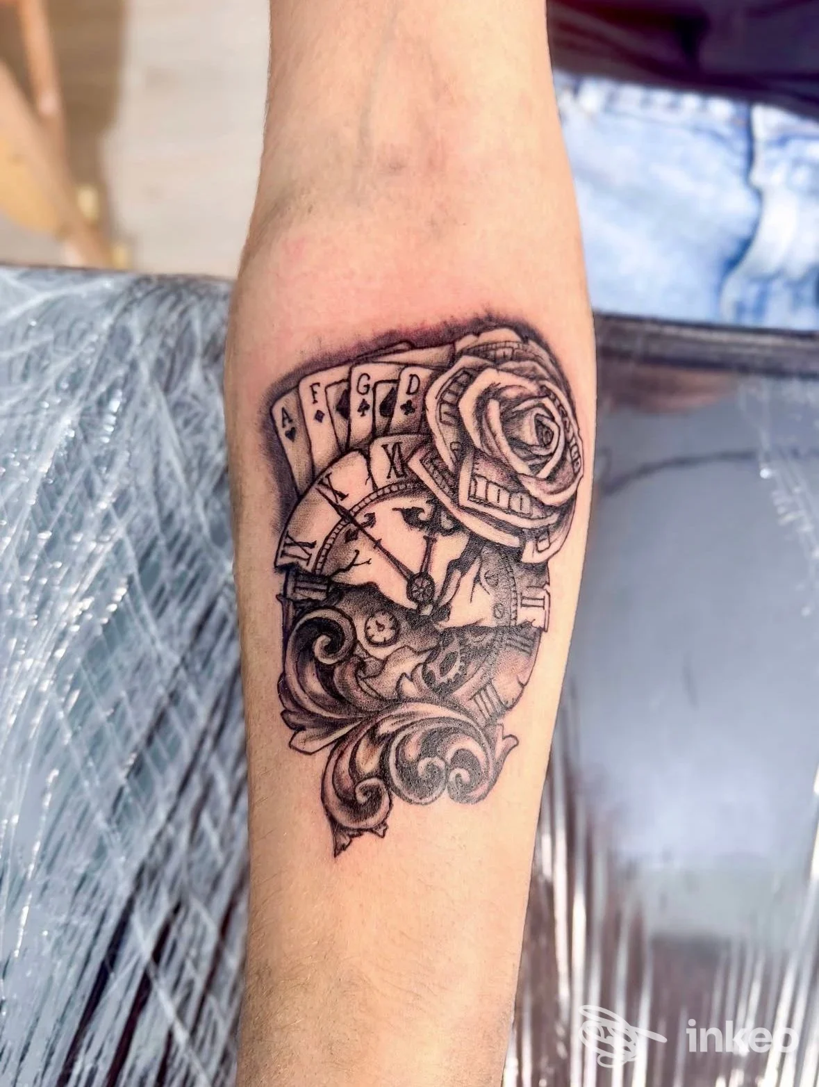 Tatuaggio in bianco e nero su avambraccio con orologio, carte e rosa, ClubHouse tattoo studio Leini.
