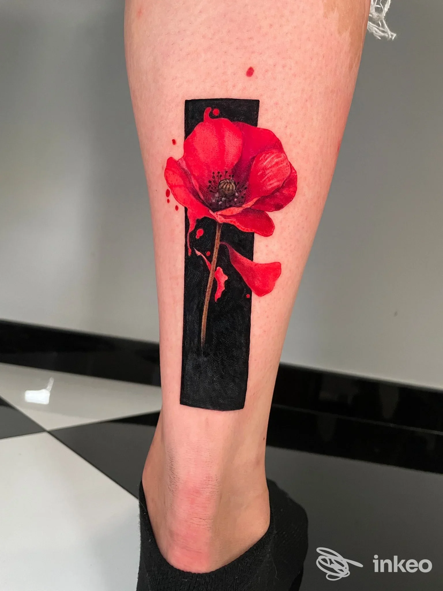 Dettaglio di un tatuaggio: papavero rosso su rettangolo nero sul polpaccio, foto dallo studio Crisantemo Tattoo, Torino.