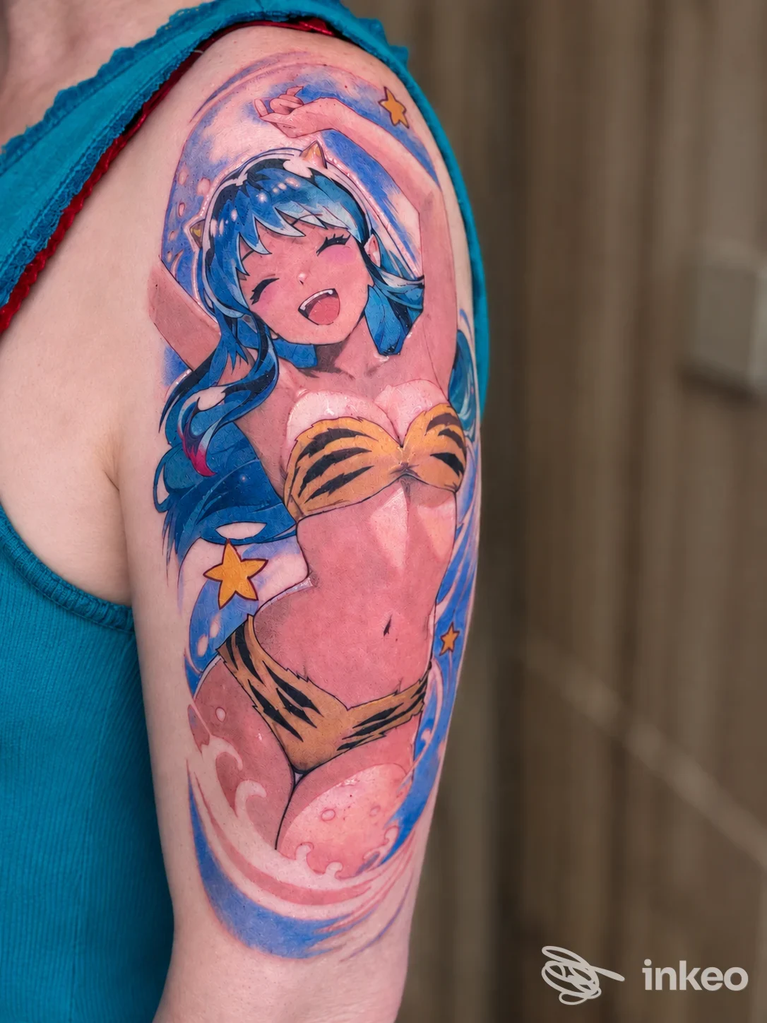 Tatuaggio colorato in stile anime sul braccio superiore con personaggio femminile sorridente, Crisantemo Tattoo, Torino.