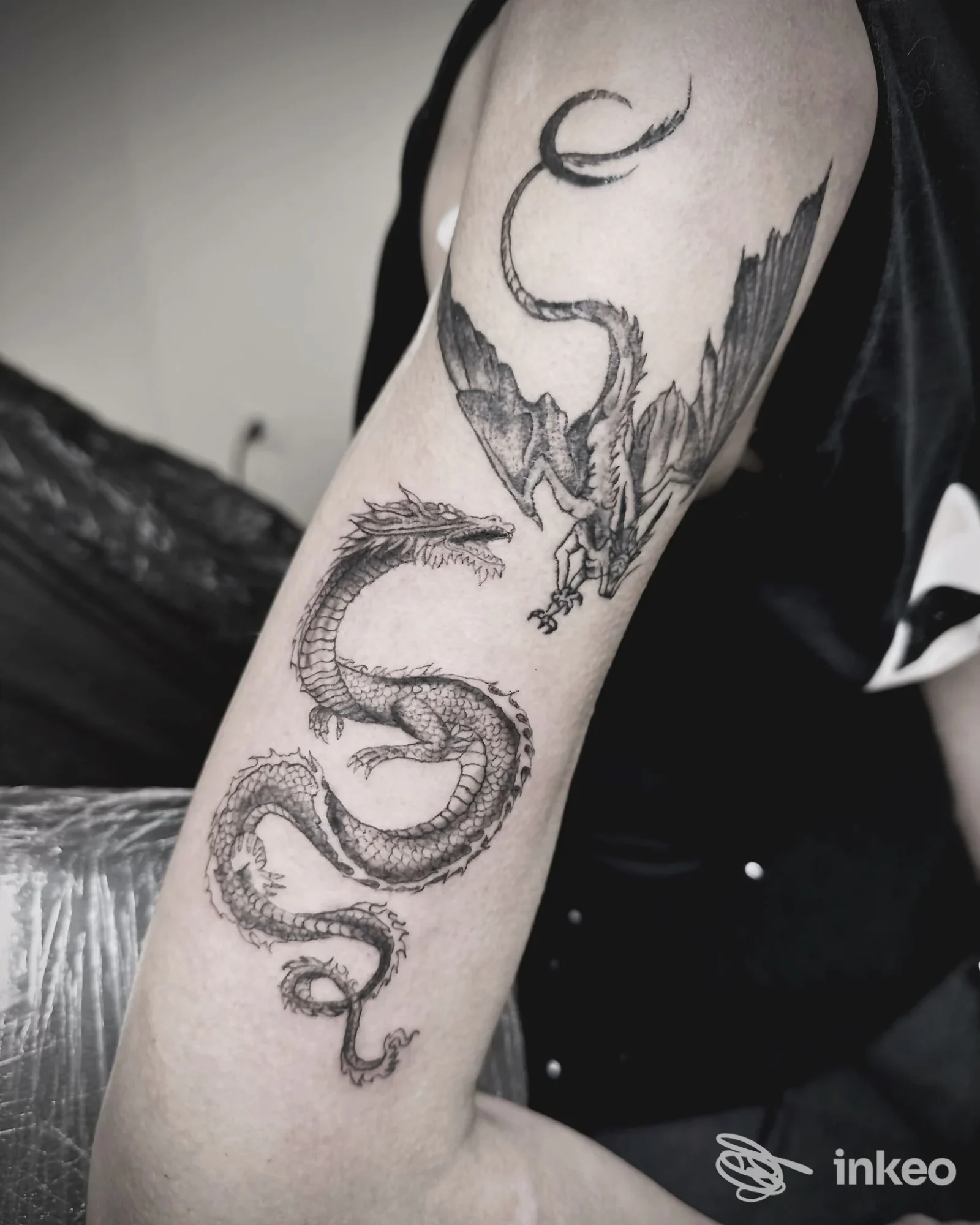 Tatuaggio a inchiostro nero di due draghi sul braccio, foto fornita da DéN Tattoo Saloon, Torino.