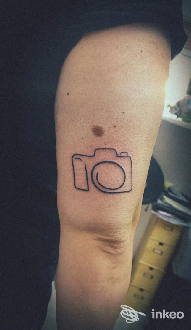 Tatuaggio minimal a forma di macchina fotografica sul braccio, DarkAngel Ink - Tattoo Studio, Chivasso.