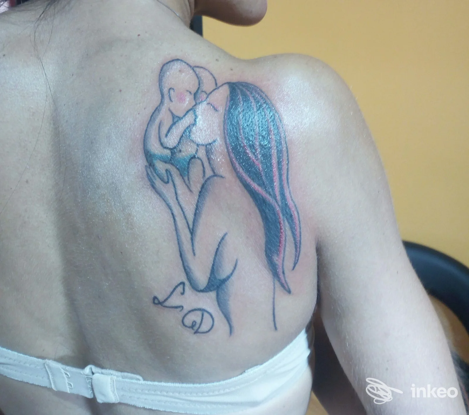 Tatuaggio su scapola sinistra raffigurante madre e bambino, foto fornita da DarkAngel Ink - Tattoo Studio, Chivasso.