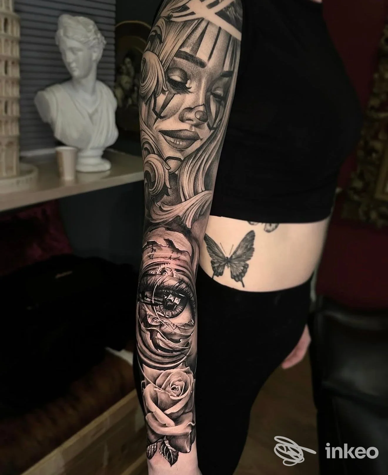Manica tatuata in bianco e nero con ritratto e rose sul braccio e farfalla sul fianco, immagine da Dope Tattoo, Bra.